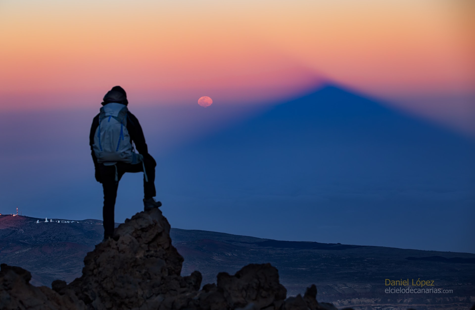 What phase of the Moon is 3.14 radians from the Sun? The Full Moon, of course. Even though the Moon might look full for several days, the Moon is truly at its full phase when it is 3.14 radians (aka 180 degrees) from the Sun in ecliptic longitude. That's opposite the Sun in planet Earth's sky. Rising as the Sun set on March 9, only an hour or so after the moment of its full phase, this orange tinted and slightly flattened Moon still looked full. It was photographed opposite the setting Sun from Teide National Park on the Canary Island of Tenerife. Also opposite the setting Sun, seen from near the Teide volcano peak about 3,500 meters above sea level, is the mountain's rising triangular shadow extending into Earth's dense atmosphere. Below the distant ridge line on the left are the white telescope domes of Teide Observatory
