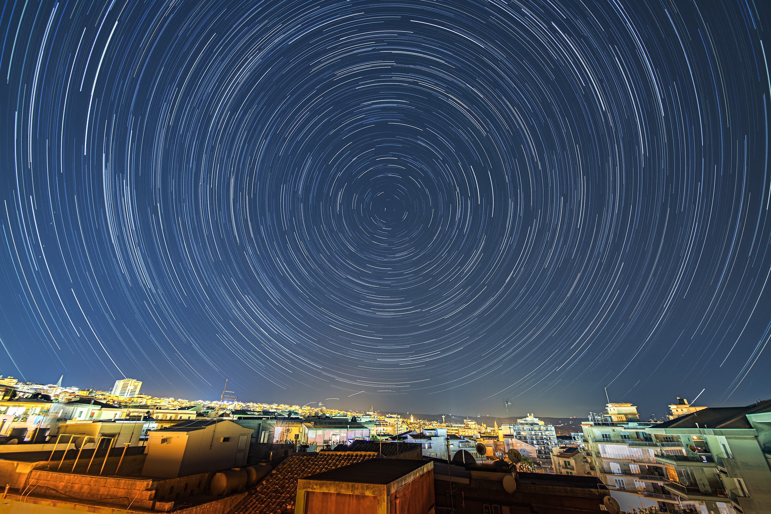 In trying times, stars still trail in the night. Taken on March 14, this night skyscape was made by combining 230 exposures each 15 seconds long to follow the stars' circular paths. The camera was fixed to a tripod on an isolated terrace near the center of Ragusa, Italy, on the island of Sicily. But the night sky was shared around the rotating planet. A friend to celestial navigators and astrophotographers alike Polaris, the north star, makes the short bright trail near the center of the concentric celestial arcs.