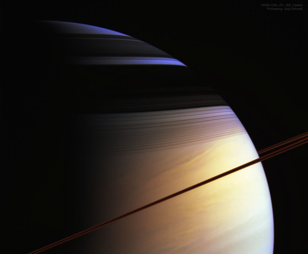 What creates Saturn's colors?  The featured picture of Saturn only slightly exaggerates what a human would see if hovering close to the giant ringed world.   The image was taken in 2005 by the robot Cassini spacecraft that orbited Saturn from 2004 to 2017.  Here Saturn's majestic rings appear directly only as a curved line, appearing brown, in part, from its infrared glow.  The rings best show their complex structure in the dark shadows they create across the upper part of the planet.   The northern hemisphere of Saturn can appear partly blue for the same reason that Earth's skies can appear blue -- molecules in the cloudless portions of both planet's atmospheres are better at scattering blue light than red.  When looking deep into Saturn's clouds, however, the natural gold hue of Saturn's clouds becomes dominant.   It is not known why southern Saturn does not show the same blue hue -- one hypothesis holds that clouds are higher there.   It is also not known why some of Saturn's clouds are colored gold.   Activities: NASA Science at Home