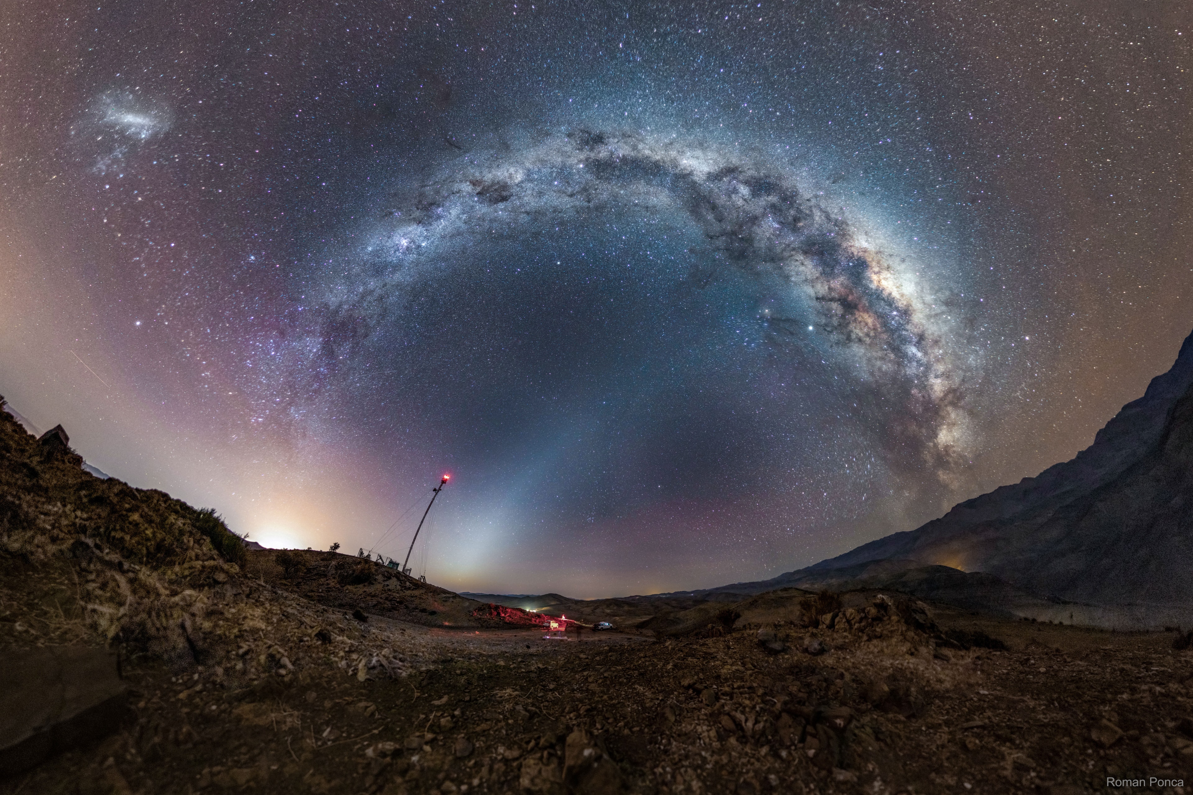 What is the band of light connecting the ground to the Milky Way?  Zodiacal light -- a stream of dust that orbits the Sun in the inner Solar System. It is most easily seen just before sunrise, where it has been called a false dawn, or just after sunset. The origin of zodiacal dust remains a topic of research, but is hypothesized to result from asteroid collisions and comet tails.  The featured wide-angle image shows the central band of our Milky Way Galaxy arching across the top, while the Large Magellanic Cloud (LMC), a satellite galaxy to our Milky Way, is visible on the far left. The image is a combination of over 30 exposures taken last July near La Serena among the mountains of Chile.  During the next two months, zodiacal light can appear quite prominent in northern skies just after sunset.   Almost Hyperspace: Random APOD Generator