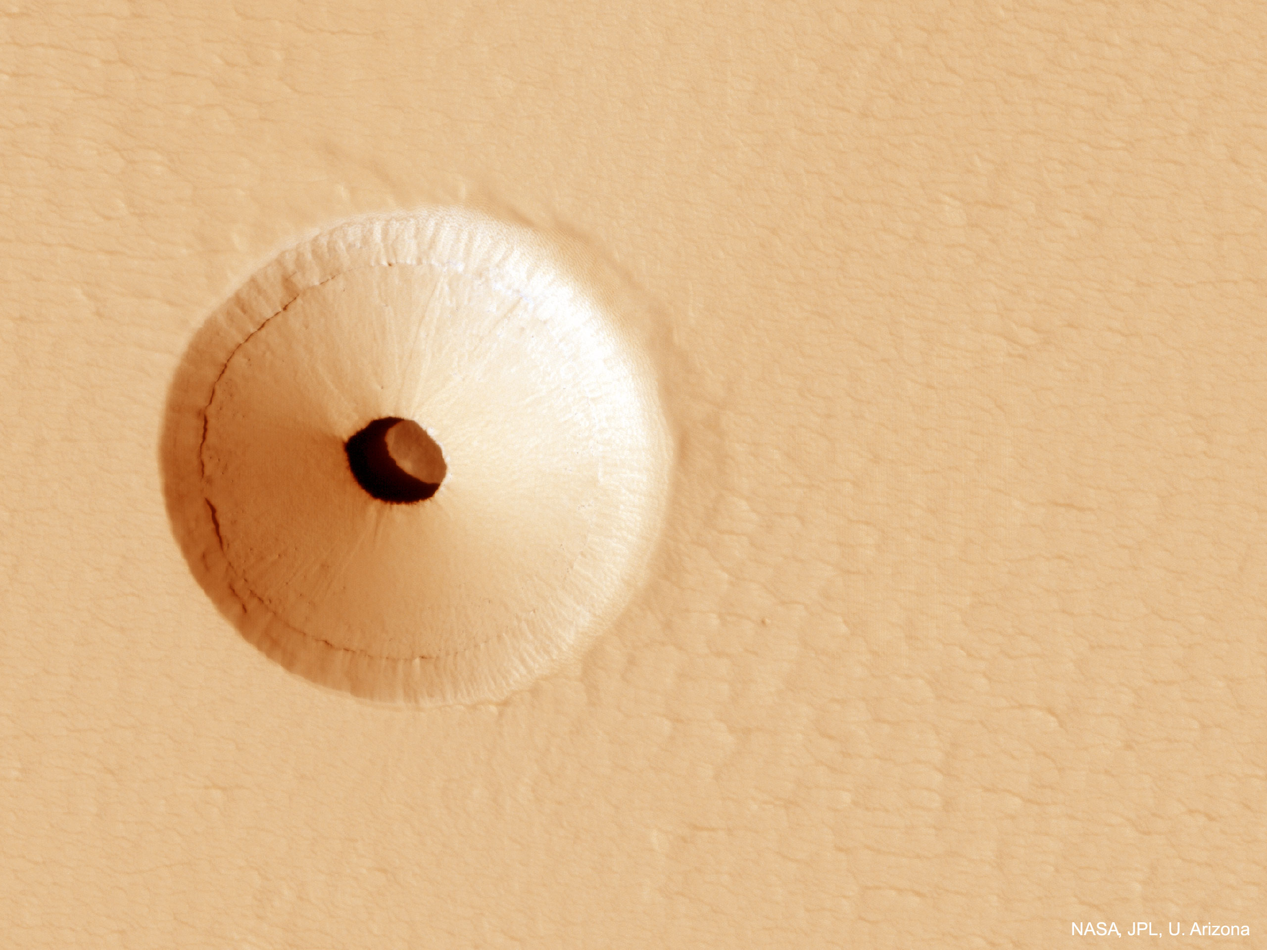 What created this unusual hole in Mars? The hole was discovered by chance in 2011 on images of the dusty slopes of Mars' Pavonis Mons volcano taken by the HiRISE instrument aboard the robotic Mars Reconnaissance Orbiter currently circling Mars. The hole, shown in representative color, appears to be an opening to an underground cavern, partly illuminated on the image right.  Analysis of this and follow-up images revealed the opening to be about 35 meters across, while the interior shadow angle indicates that the underlying cavern is roughly 20 meters deep. Why there is a circular crater surrounding this hole remains a topic of speculation, as is the full extent of the underlying cavern. Holes such as this are of particular interest because their interior caves are relatively protected from the harsh surface of Mars, making them relatively good candidates to contain Martian life. These pits are therefore prime targets for possible future spacecraft, robots, and even human interplanetary explorers.