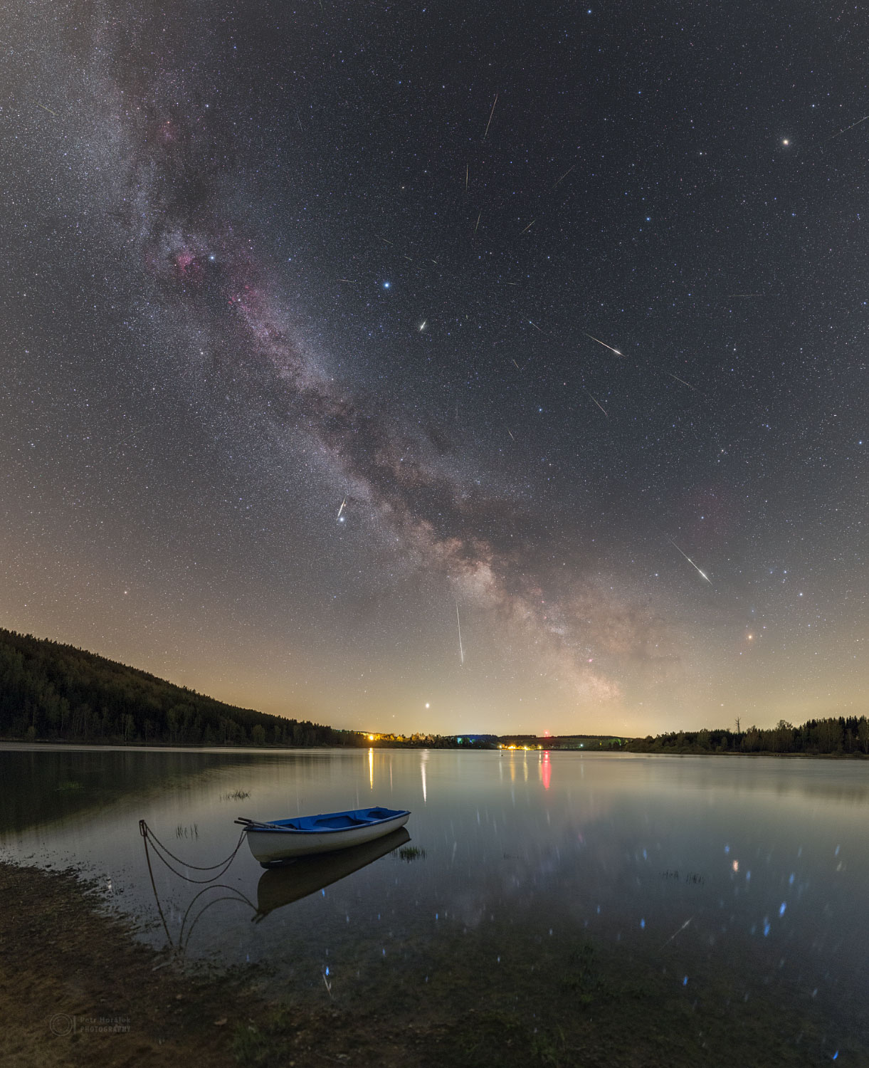 Where are all of these meteors coming from?  In terms of direction on the sky, the pointed answer is the constellation of Small Harp (Lyra).  That is why the famous meteor shower that peaks every April is known as the Lyrids -- the meteors all appear to came from a radiant toward Lyra. In terms of parent body, though, the sand-sized debris that makes up the Lyrid meteors come from Comet Thatcher. The comet follows a well-defined orbit around our Sun, and the part of the orbit that approaches Earth is superposed in front of Lyra. Therefore, when Earth crosses this orbit, the radiant point of falling debris appears in Lyra. Featured here, a composite image containing over 33 meteors (can you find them all?) from last month's  Lyrid meteor shower shows several bright meteors that streaked over a shore of Seč Lake in the Czech Republic. Also visible are the bright stars Vega and Altair, the planet Jupiter, and the central band of our Milky Way Galaxy.   Notable APOD Submissions: Lyrid Meteor Shower 2020
