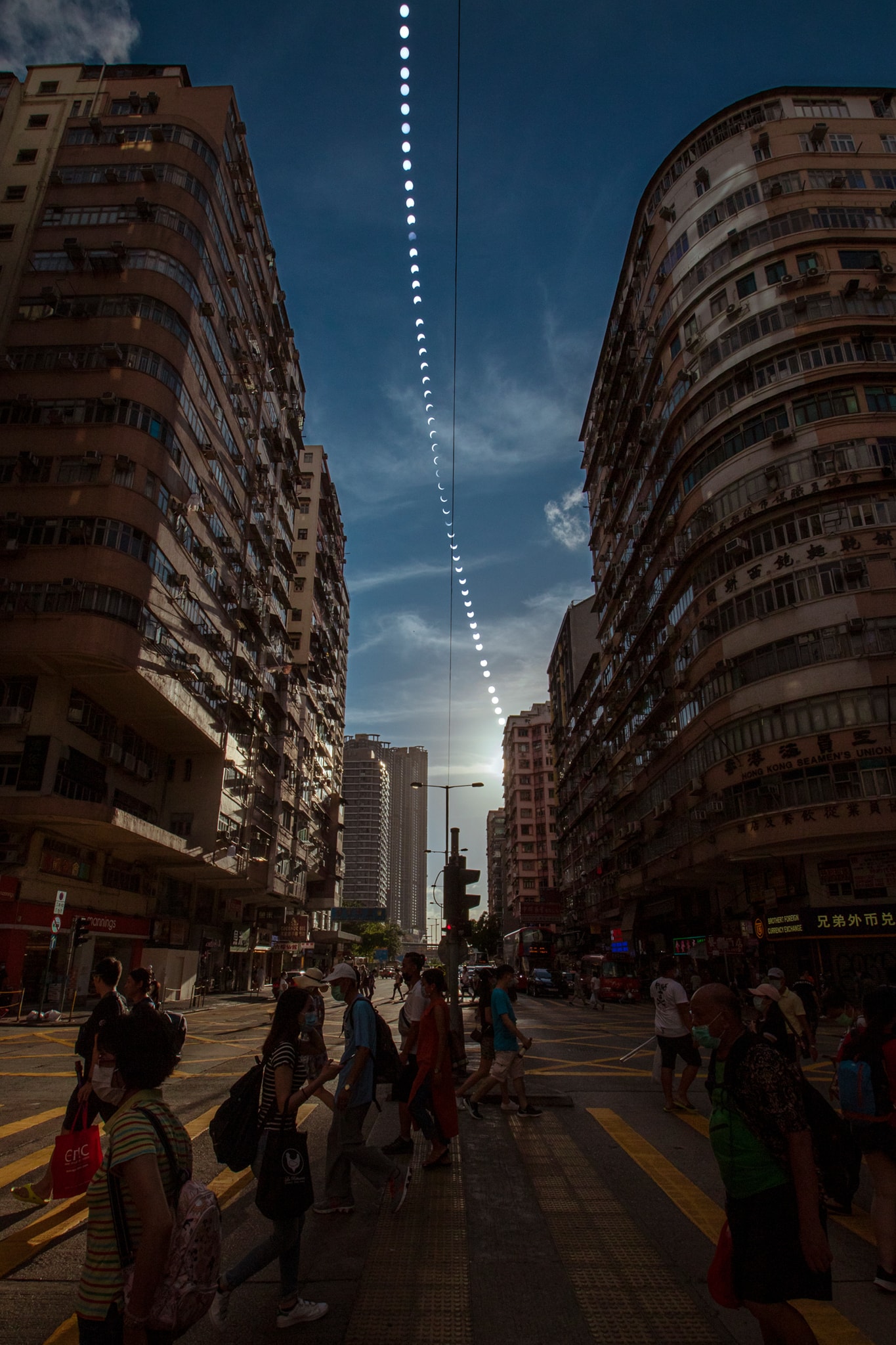 On June 21 an annular solar eclipse came soon after the solstice and our fair planet's northernmost sunset for 2020. At maximum eclipse, the New Moon in silhouette created a ring of fire visible along a narrow path at most 85 kilometers wide. The annular eclipse path began in central Africa, crossed south Asia and China, and ended over the Pacific Ocean. But a partial eclipse of the Sun was visible over a much broader region. In Hong Kong, this busy section of Jordan Street looks to the northwest, well-aligned with the track of the near solstice afternoon Sun. The street level view was composited with an eclipse sequence made with a safe solar filter on the camera. For that location the eclipse was partial. The Moon covered about 90 percent of the Sun's diameter at maximum, seen near the middle of the eclipse sequence.   Gallery: Notable images of the Annular Solar Eclipse of 2020 June submitted to APOD
