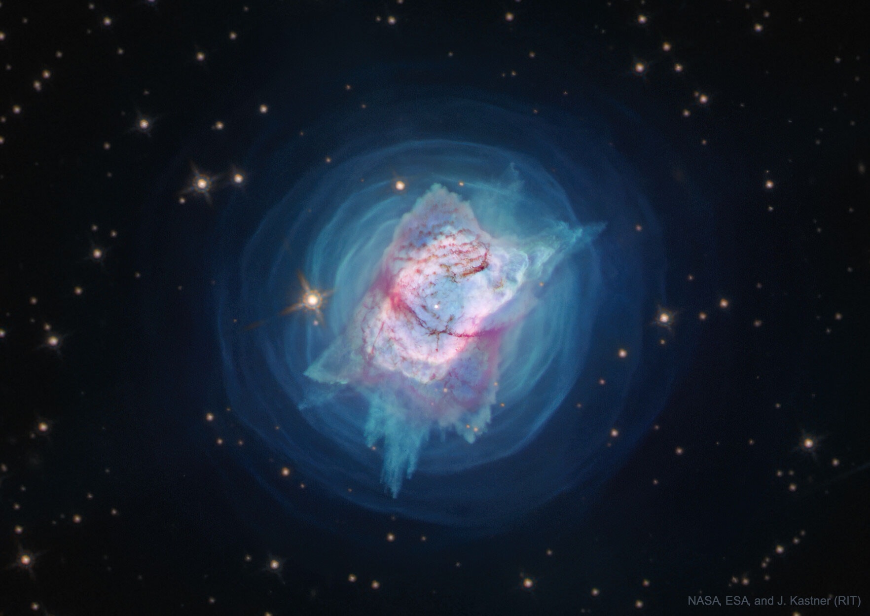 What created this unusual planetary nebula? NGC 7027 is one of the smallest, brightest, and most unusually shaped planetary nebulas known. Given its expansion rate, NGC 7027 first started expanding, as visible from Earth, about 600 years ago.  For much of its history, the planetary nebula has been expelling shells, as seen in blue in the featured image.  In modern times, though, for reasons unknown, it began ejecting gas and dust (seen in red) in specific directions that created a new pattern that seems to have four corners. These shells and patterns have been mapped in impressive detail by recent images from the Wide Field Camera 3 onboard the Hubble Space Telescope.  What lies at the nebula's center is unknown, with one hypothesis holding it to be a close binary star system where one star sheds gas onto an erratic disk orbiting the other star. NGC 7027, about 3,000 light years away, was first discovered in 1878 and can be seen with a standard backyard telescope toward the constellation of the Swan (Cygnus).