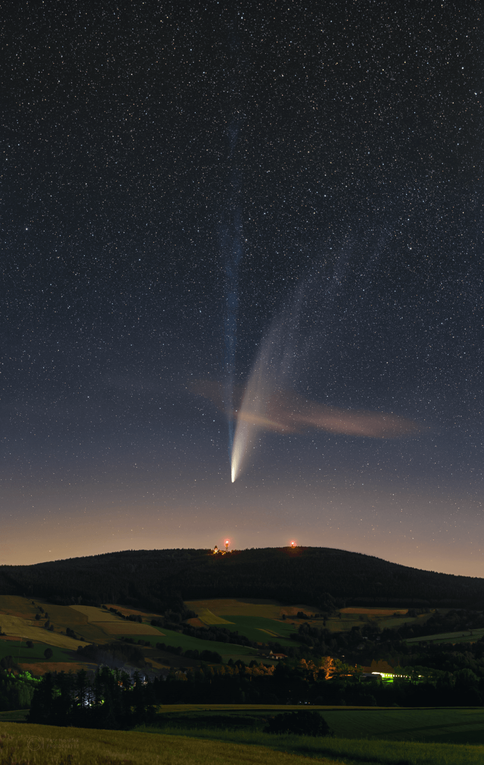 This Comet NEOWISE (C/2020 F3) now sweeps through our fair planet's northern skies. Its long tails stretch across this deep skyview from Suchy Vrch, Czech Republic. Recorded on the night of July 13/14, the composite of untracked foreground and tracked and filtered sky exposures teases out details in the comet's tail not visible to the unaided eye. Faint structures extend to the top of the frame, over 20 degrees from the comet's bright coma. Pushed out by the pressure of sunlight itself, the broad curve of the comet's yellowish dust tail is easy to see by eye. But the fainter, more bluish tail is separate from the reflective comet dust. The fainter tail is an ion tail, formed as ions from the cometary coma are dragged outward by magnetic fields in the solar wind and fluoresce in the sunlight. Outbound NEOWISE is climbing higher in northern evening skies, coming closest to Earth on July 23rd.  Comet NEOWISE Images: July 15 | July 14 | July 13 | July 12 | July 11 | July 10 & earlier