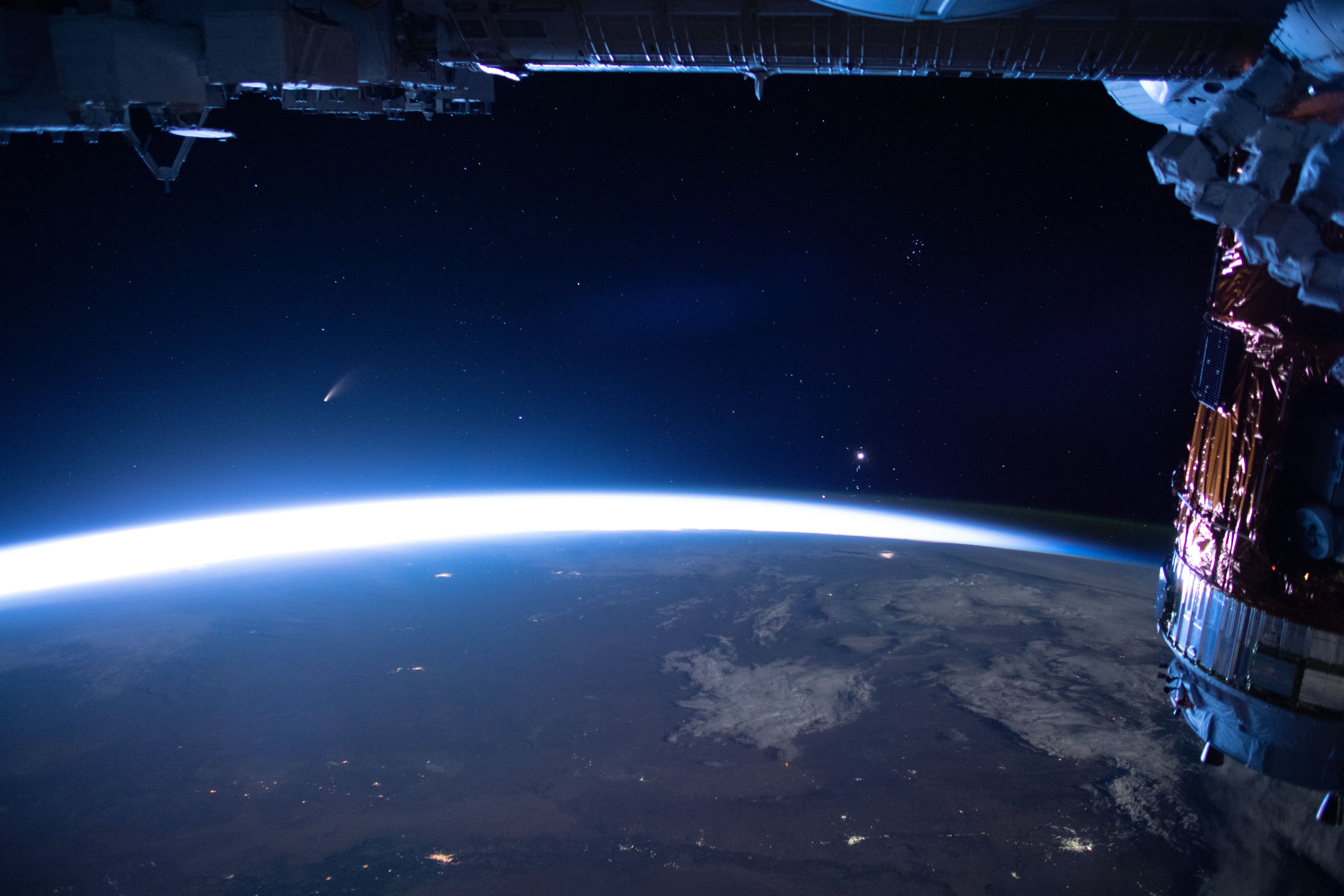 Rounding the Sun on July 3rd and currently headed for the outer Solar System, Comet NEOWISE (C/2020 F3) has been growing brighter in the predawn skies of planet Earth. From low Earth orbit it also rises before the Sun, captured above the approaching glow along the eastern horizon in this snapshot from the International Space Station on July 5. Venus, now Earth's morning star is the brilliant celestial beacon on the right in the field of view. Above Venus you can spot the sister stars of the more compact Pleiades cluster. Earthbound skygazers can spot this comet with the unaided eye, but should look for awesome views with binoculars.   Comet NEOWISE from Earth's Surface: Notable Images Submitted to APOD