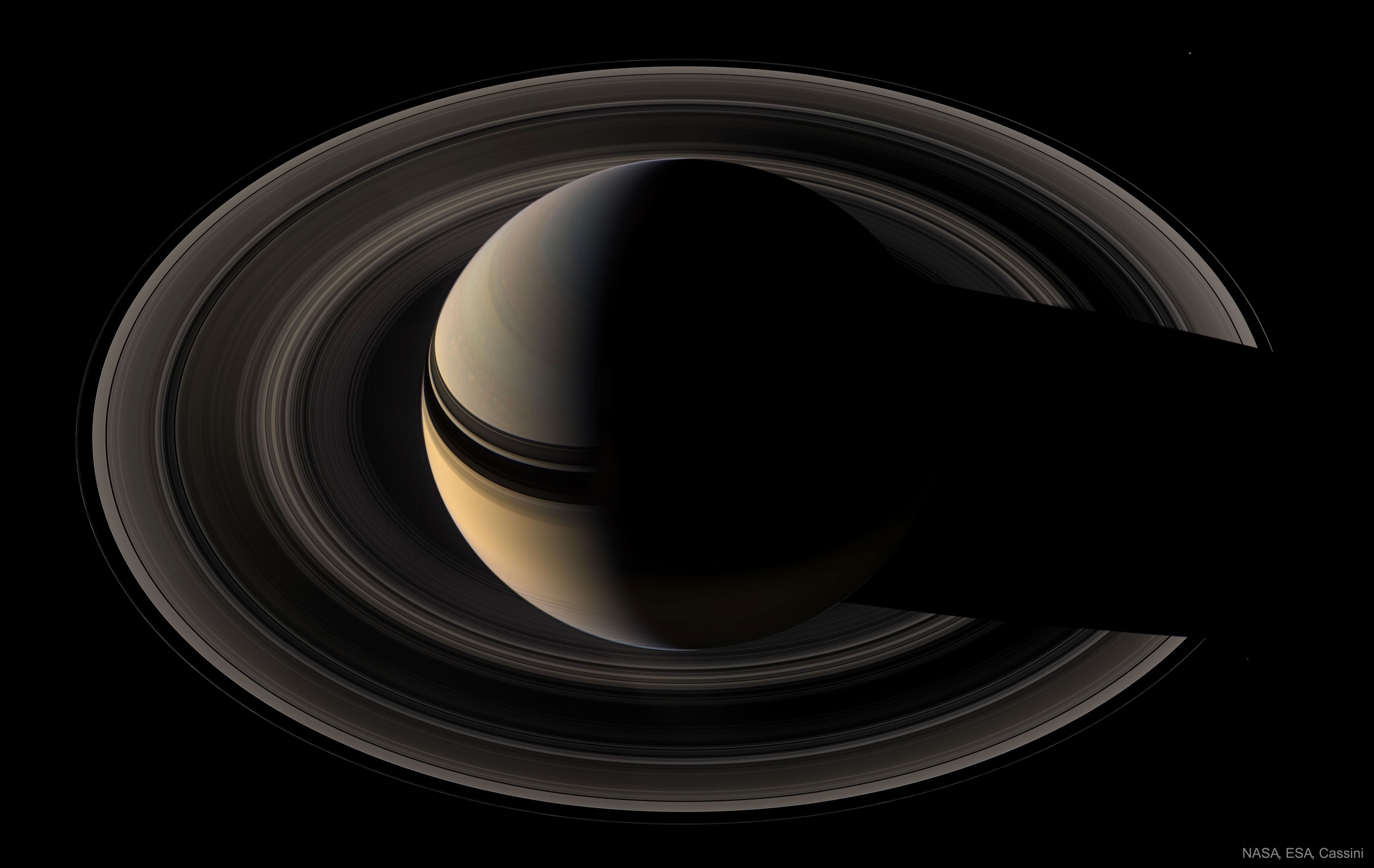 From Earth, Saturn never shows a crescent phase. But when viewed from a spacecraft the majestic giant planet can show just a sunlit slice. This image of crescent Saturn in natural color was taken by the robotic Cassini spacecraft in 2007. It captures Saturn's rings from the side of the ring plane opposite the Sun -- the unilluminated side -- another vista not visible from Earth. Visible are subtle colors of cloud bands, the complex shadows of the rings on the planet, and the shadow of the planet on the rings. The moons Mimas, at 2 o'clock, and Janus 4 o'clock, can be seen as specks of light, but the real challenge is to find Pandora (8 o'clock).  From Earth, Saturn's disk is nearly full now and opposite the Sun. Along with bright fellow giant planet Jupiter it rises in the early evening.