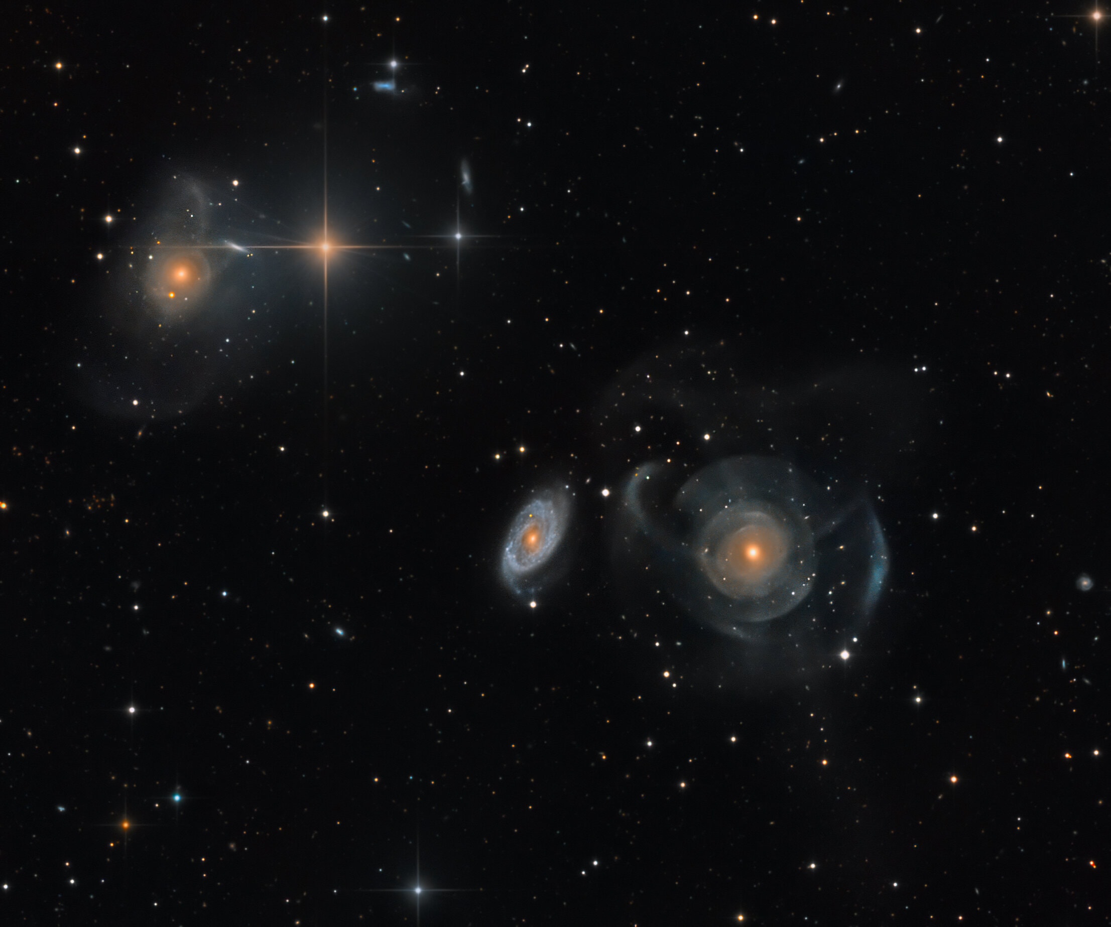 This intergalactic skyscape features a peculiar system of galaxies cataloged as Arp 227 some 100 million light-years distant. Swimming within the boundaries of the constellation Pisces, Arp 227 consists of the two galaxies prominent right of center, the curious shell galaxy NGC 474 and its blue, spiral-armed neighbor NGC 470. The faint, wide arcs or shells of NGC 474 could have been formed by a gravitational encounter with neighbor NGC 470. Alternately the shells could be caused by a merger with a smaller galaxy producing an effect analogous to ripples across the surface of a pond. The large galaxy on the top lefthand side of the deep image, NGC 467, appears to be surrounded by faint shells too, evidence of another interacting galaxy system. Intriguing background galaxies are scattered around the field that also includes spiky foreground stars. Of course, those stars lie well within our own Milky Way Galaxy. The field of view spans 25 arc minutes or about 1/2 degree on the sky.