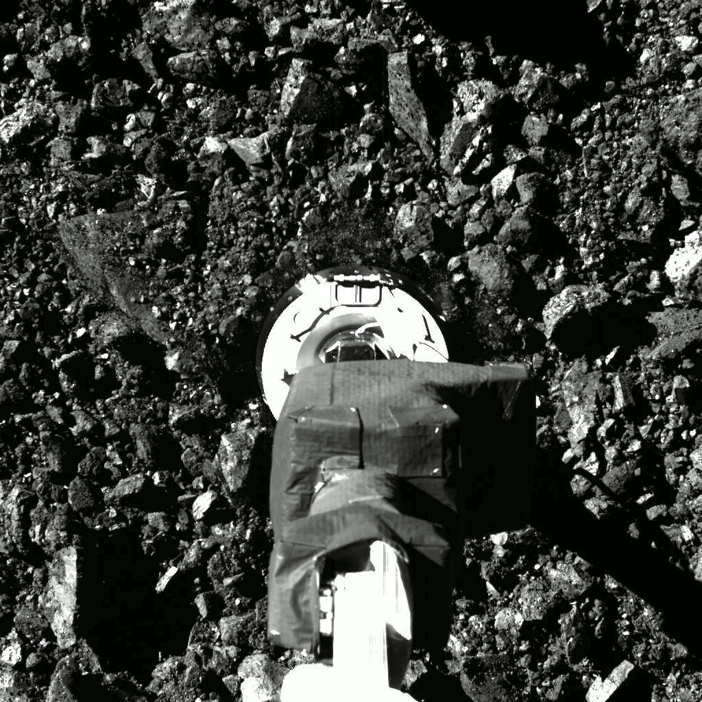 On October 20, after a careful approach to the boulder-strewn surface, the OSIRIS-REx spacecraft's arm reached out and touched asteroid Bennu. Dubbed a Touch-And-Go (TAG) sampling event, the 30 centimeter wide sampling head (TAGSAM) appears to crush some of the rocks in this snapshot. The close-up scene was recorded by the spacecraft's SamCam some 321 million kilometers from planet Earth, just after surface contact. One second later, the spacecraft fired nitrogen gas from a bottle intended to blow a substantial amount of Bennu's regolith into the sampling head, collecting the loose surface material. Data show the spacecraft spent approximately 5 more seconds in contact with Bennu's Nightingale sample site and then performed its back-away burn. Timelapse frames from SamCam reveal the aftermath.