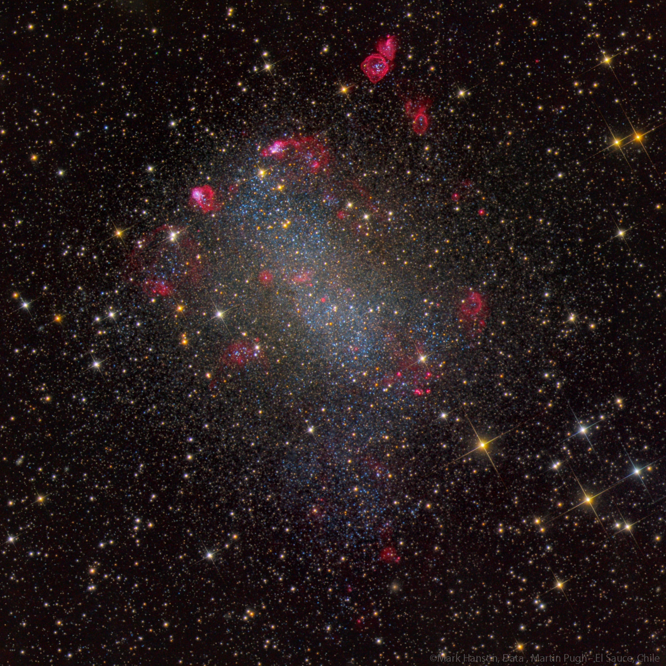 Grand spiral galaxies often seem to get all the glory, flaunting their young, bright, blue star clusters in beautiful, symmetric spiral arms. But small galaxies form stars too, like nearby NGC 6822, also known as Barnard's Galaxy. Beyond the rich starfields in the constellation Sagittarius, NGC 6822 is a mere 1.5 million light-years away, a member of our Local Group of galaxies. A dwarf irregular galaxy similar to the Small Magellanic Cloud, NGC 6822 is about 7,000 light-years across. Brighter foreground stars in our Milky Way have a spiky appearance. Behind them, Barnard's Galaxy is seen to be filled with young blue stars and mottled with the telltale pinkish hydrogen glow of star forming regions in this deep color composite image.