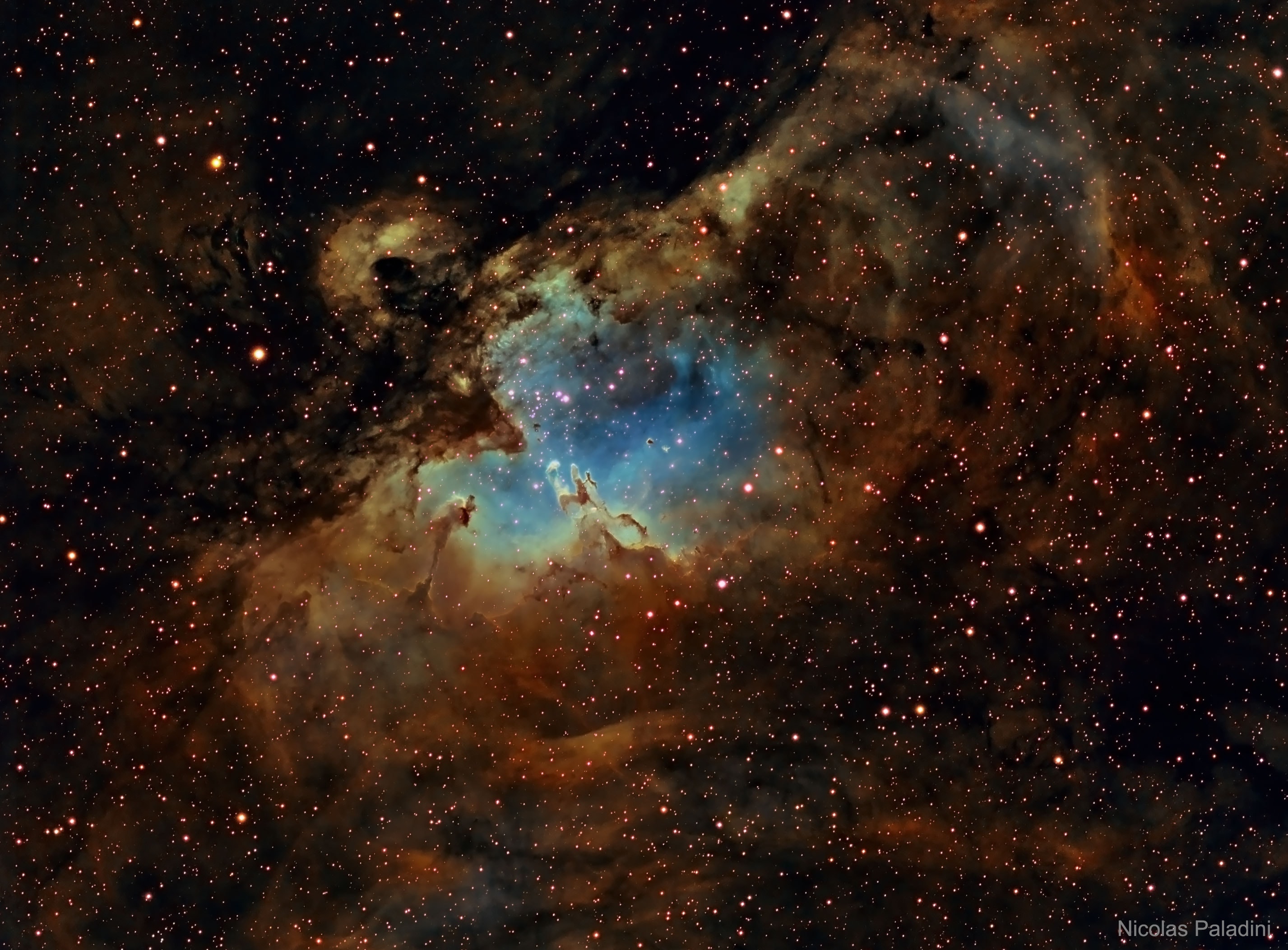 From afar, the whole thing looks like an Eagle.  A closer look at the Eagle Nebula, however, shows the bright region is actually a window into the center of a larger dark shell of dust.  Through this window, a brightly-lit workshop appears where a whole open cluster of stars is being formed.  In this cavity tall pillars and round globules of dark dust and cold molecular gas remain where stars are still forming.  Already visible are several young bright blue stars whose light and winds are burning away and pushing back the remaining filaments and walls of gas and dust.  The Eagle emission nebula, tagged M16, lies about 6500 light years away, spans about 20 light-years, and is visible with binoculars toward the constellation of the Serpent (Serpens).  This picture involved over 12 hours of imaging and combines three specific emitted colors emitted by sulfur (colored as red), hydrogen (yellow), and oxygen (blue).   Gallery: Notable images of the recent Total Solar Eclipse submitted to APOD