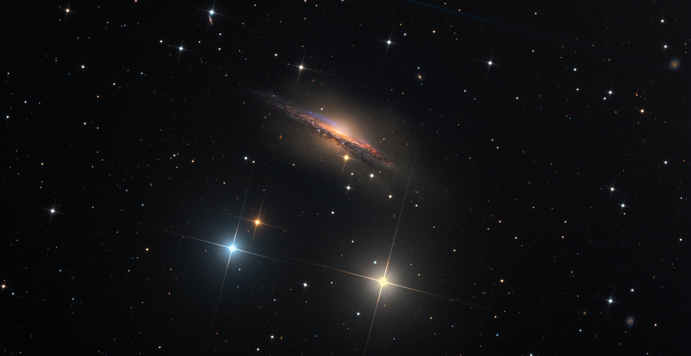 Big, beautiful spiral galaxy NGC 1055 is a dominant member of a small galaxy group a mere 60 million light-years away toward the aquatically intimidating constellation Cetus. Seen edge-on, the island universe spans over 100,000 light-years, a little larger than our own Milky Way galaxy. The colorful, spiky stars decorating this cosmic portrait of NGC 1055 are in the foreground, well within the Milky Way. But the telltale pinkish star forming regions are scattered through winding dust lanes along the distant galaxy's thin disk. With a smattering of even more distant background galaxies, the deep image also reveals a boxy halo that extends far above and below the central bluge and disk of NGC 1055. The halo itself is laced with faint, narrow structures, and could represent the mixed and spread out debris from a satellite galaxy disrupted by the larger spiral some 10 billion years ago.