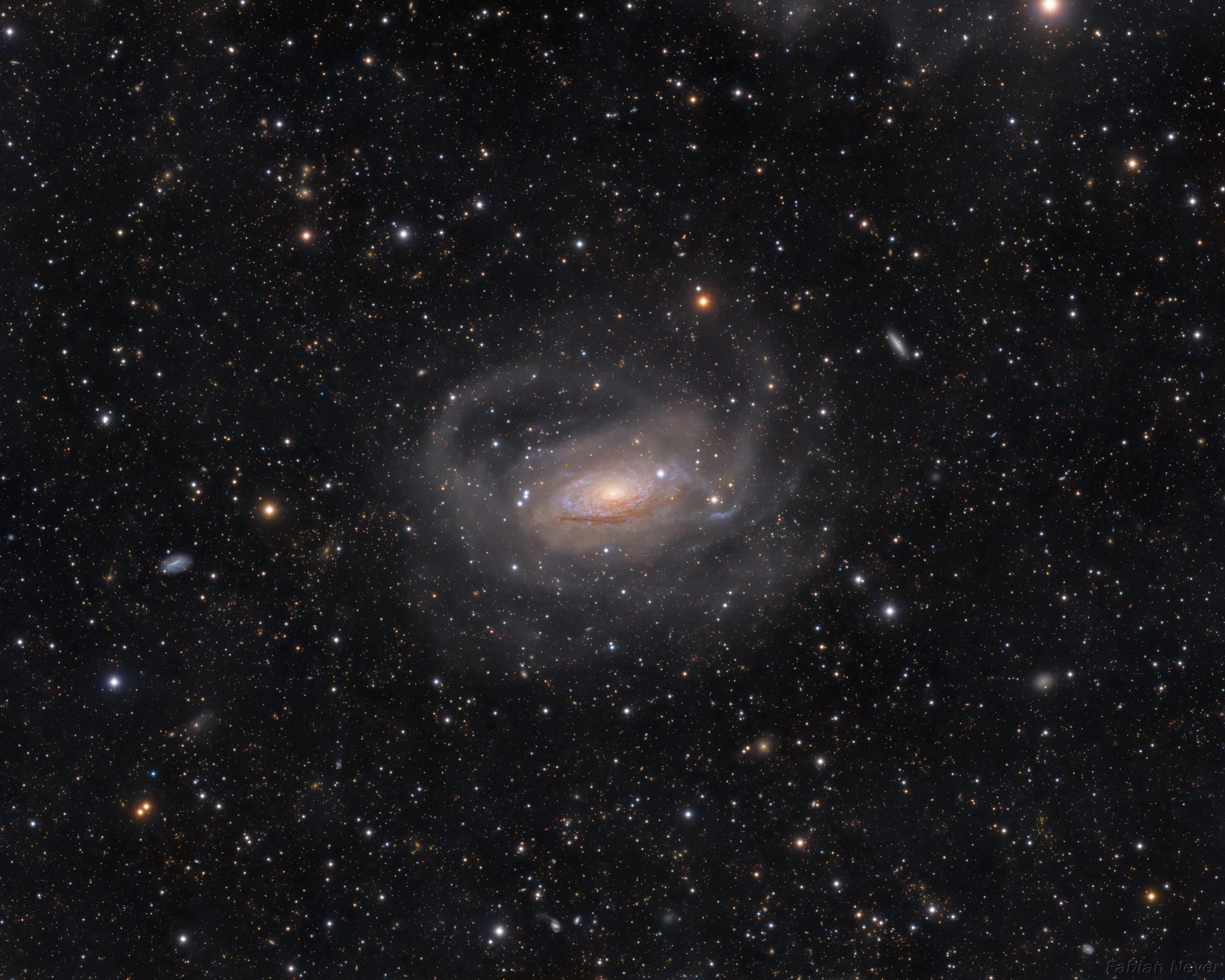 A bright spiral galaxy of the northern sky, Messier 63 is nearby, about 30 million light-years distant toward the loyal constellation Canes Venatici. Also cataloged as NGC 5055, the majestic island universe is nearly 100,000 light-years across, about the size of our own Milky Way. Its bright core and majestic spiral arms lend the galaxy its popular name, The Sunflower Galaxy, while this exceptionally deep exposure also follows faint, arcing star streams far into the galaxy's halo. Extending nearly 180,000 light-years from the galactic center the star streams are likely remnants of tidally disrupted satellites of M63. Other satellite galaxies of M63 can be spotted in this remarkable wide-field image, made with a small telescope, including five newly identified faint dwarf galaxies, which could contribute to M63's star streams in the next few billion years.