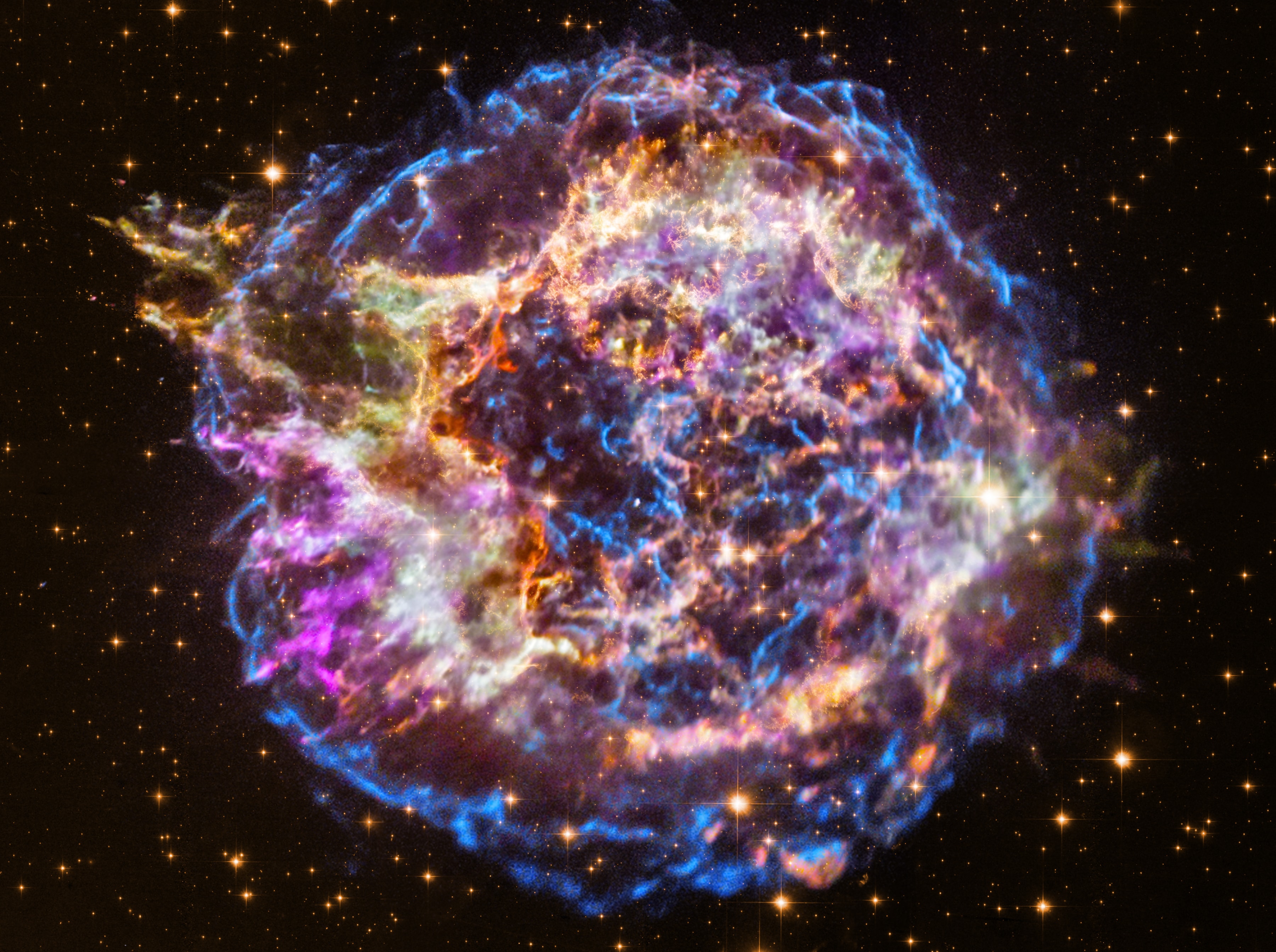 Massive stars in our Milky Way Galaxy live spectacular lives.  Collapsing from vast cosmic clouds, their nuclear furnaces ignite and create heavy elements in their cores. After a few million years, the enriched material is blasted back into interstellar space where star formation can begin anew. The expanding debris cloud known as Cassiopeia A is an example of this final phase of the stellar life cycle. Light from the explosion which created this supernova remnant would have been first seen in planet Earth's sky about 350 years ago, although it took that light about 11,000 years to reach us. This false-color image, composed of X-ray and optical image data from the Chandra X-ray Observatory and Hubble Space Telescope, shows the still hot filaments and knots in the remnant. It spans about 30 light-years at the estimated distance of Cassiopeia A. High-energy X-ray emission from specific elements has been color coded, silicon in red, sulfur in yellow, calcium in green and iron in purple, to help astronomers explore the recycling of our galaxy's star stuff. Still expanding, the outer blast wave is seen in blue hues. The bright speck near the center is a neutron star, the incredibly dense, collapsed remains of the massive stellar core.