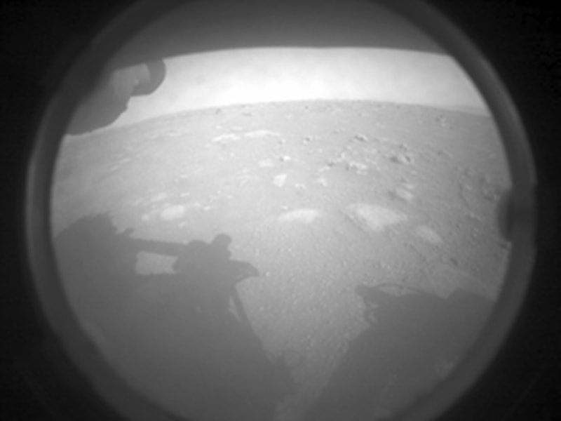 After a 203 day interplanetary voyage, and seven minutes of terror, Perseverance has landed on Mars.  Confirmation of the successful landing at Jezero crater was announced from mission control at NASA’s Jet Propulsion Laboratory in Southern California at 12:55 pm PST on February 18. The car-sized Mars rover's Front Left Hazard Avoidance Camera acquired this initial low resolution image shortly after touchdown on mission Sol 0. A protective cover is still on the camera, but the shadow of Perseverance, now the most ambitious rover sent to the Red Planet, is visible cast across the martian surface.