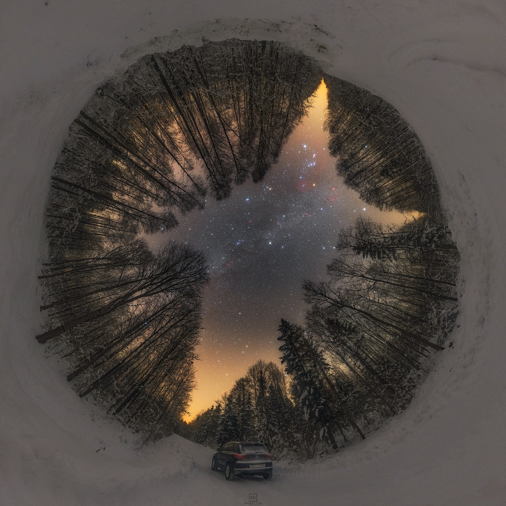 Snow blankets the ground in this serene forest and sky view. Assembled in a 360 degree panoramic projection, the mosaicked frames were captured at January's end along a quiet country road near Siemiony, northeastern Poland, planet Earth. The night was cold and between trees reaching toward the sky shine the stars and nebulae of the northern winter Milky Way. Near zenith is bright star Capella, a mere 43 light-years above the tree tops. Alpha star of the constellation Auriga the Charioteer and part of the winter hexagon asterism, Capella is a well-studied double star system. Follow the Milky Way above and right of Capella and you might spot the familiar stars of Orion in the northern winter night.