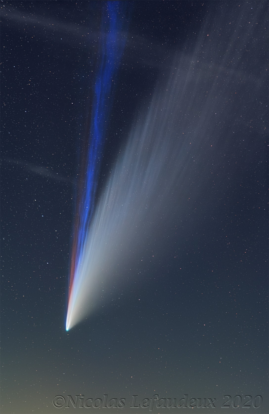 What created the unusual red tail in Comet NEOWISE? Sodium.  A spectacular sight back in the summer of 2020, Comet NEOWISE, at times, displayed something more than just a surprisingly striated white dust tail and a pleasingly patchy blue ion tail. Some color sensitive images showed an unusual red tail, and analysis showed much of this third tail's color was emitted by sodium.  Gas rich in sodium atoms might have been liberated from Comet NEOWISE's warming nucleus in early July by bright sunlight, electrically charged by ultraviolet sunlight, and then pushed out by the solar wind. The featured image was captured in mid-July from Brittany, France and shows the real colors. Sodium comet tails have been seen before but are rare -- this one disappeared by late July.  Comet C/2020 F3 (NEOWISE) has since faded, lost all of its bright tails, and now approaches the orbit of Jupiter as it heads back to the outer Solar System, to return only in about 7,000 years.    Astrophysicists: Browse 2,400+ codes in the Astrophysics Source Code Library