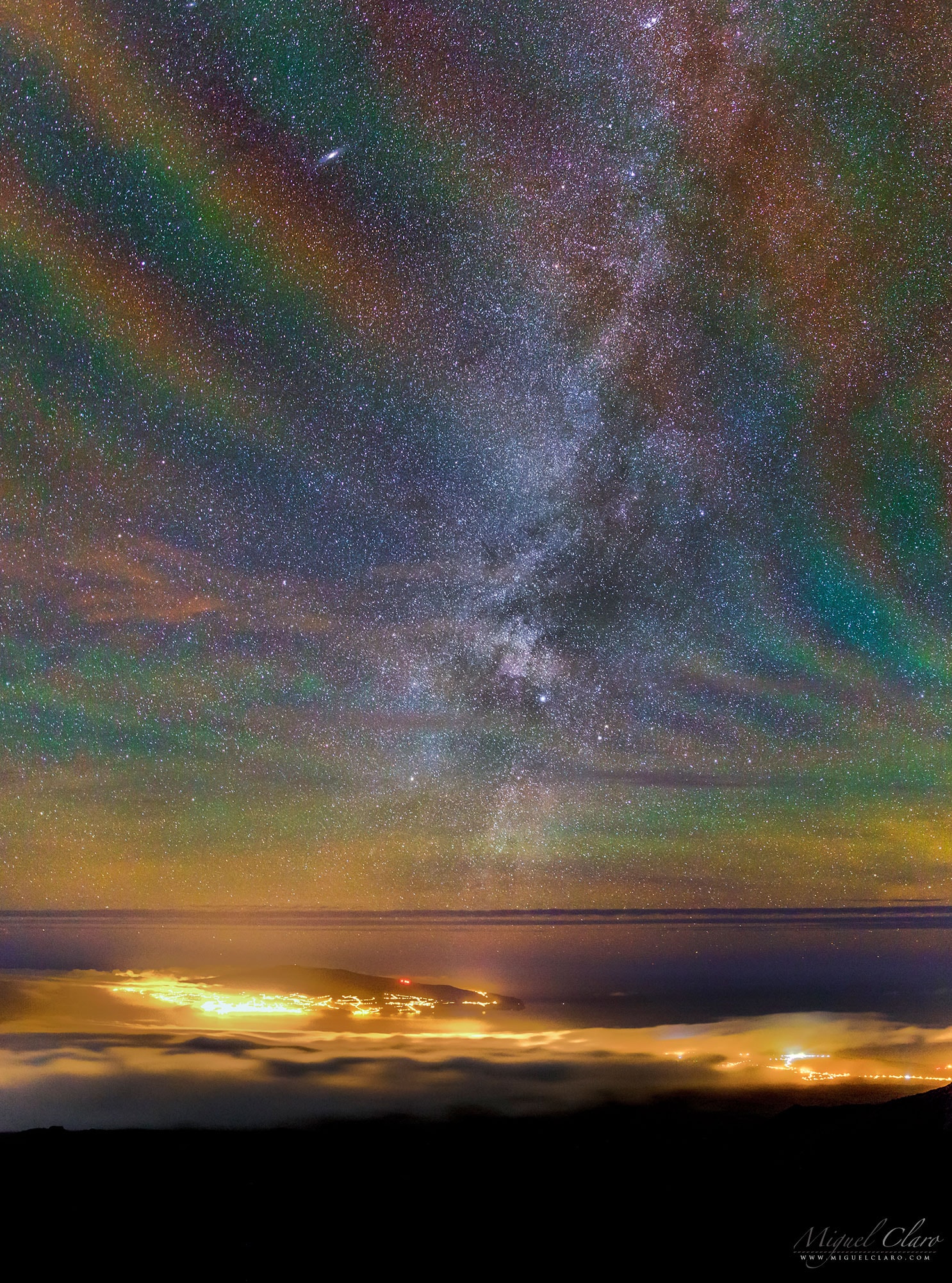 Why would the sky glow like a giant repeating rainbow?  Airglow.  Now air glows all of the time, but it is usually hard to see. A disturbance however -- like an approaching storm -- may cause noticeable rippling in the Earth's atmosphere. These gravity waves are oscillations in air analogous to those created when a rock is thrown in calm water.  The long-duration exposure nearly along the vertical walls of airglow likely made the undulating structure particularly visible.  OK, but where do the colors originate?  The deep red glow likely originates from OH molecules about 87-kilometers high, excited by ultraviolet light from the Sun. The orange and green airglow is likely caused by sodium and oxygen atoms slightly higher up.  The featured image was captured during a climb up Mount Pico in the Azores of Portugal.  Ground lights originate from the island of Faial in the Atlantic Ocean.  A spectacular sky is visible through this banded airglow, with the central band of our Milky Way Galaxy running up the image center, and M31, the Andromeda Galaxy, visible near the top left.   Explore Your Universe: Random APOD Generator