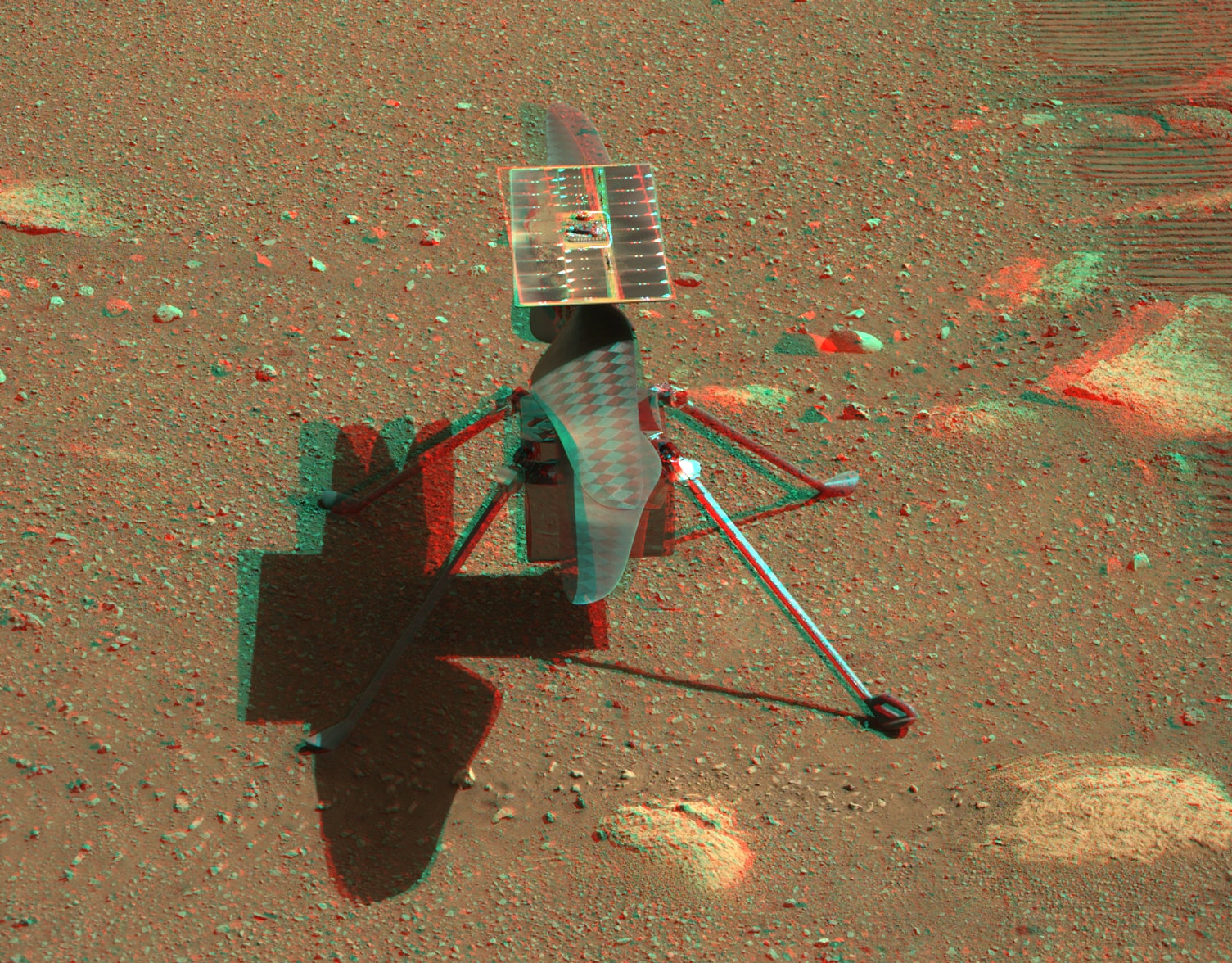 The multicolor, stereo imaging Mastcam-Z on the Perseverance rover zoomed in to captured this 3D close-up (get out your red/blue glasses) of the Mars Ingenuity helicopter on mission sol 45, April 5. That's only a few sols before the technology demonstrating Ingenuity will attempt to fly in the thin martian atmosphere, making the first powered flight on another planet. The historic test flight is planned for no earlier than Sunday, April 11.  Casting its shadow on the martian surface, Ingenuity is standing alone on four landing legs next to the rover's wheel tracks. The experimental helicopter's solar panel, charging batteries that keep it warm through the cold martian nights and power its flight, sits above its two 1.2 meter (4 foot) long counter-rotating blades.
