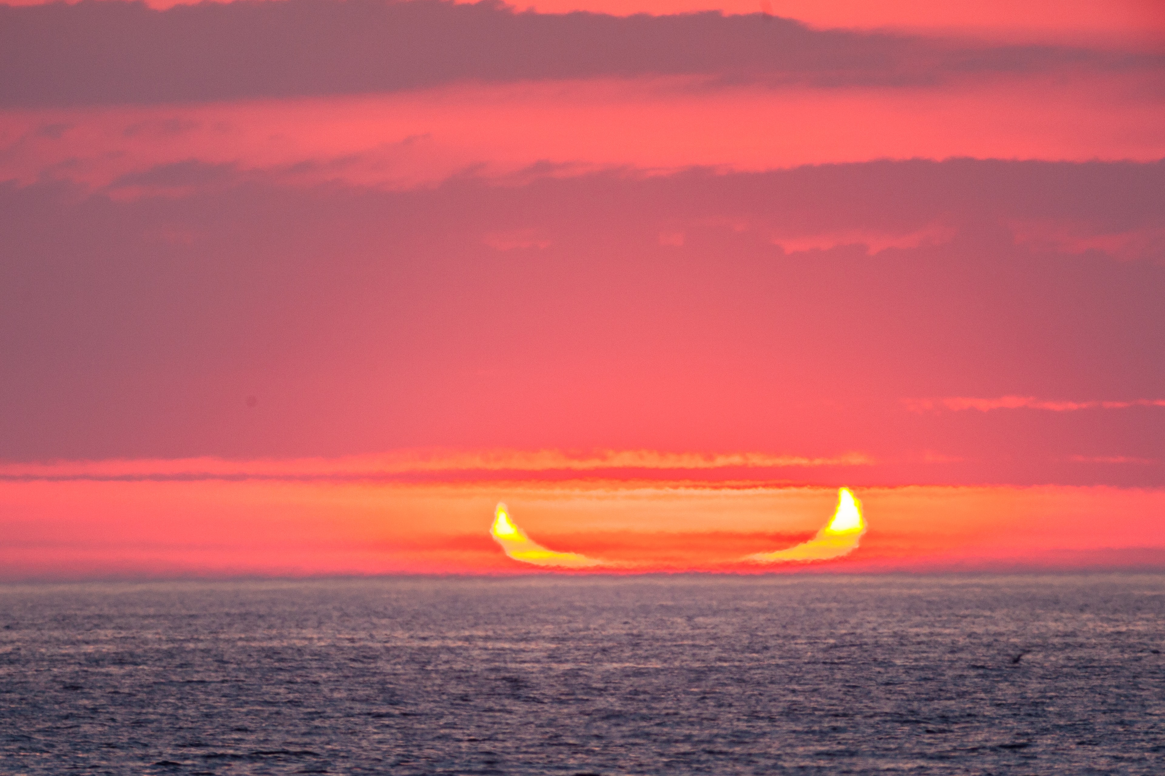 Atmospheric refraction flattened the solar disk and distorted its appearance in this telescopic view of an Atlantic sunrise on June 10. From Belmar, New Jersey on the US east coast, the scene was recorded at New Moon during this season's annular solar eclipse. The Moon in partial silhouette gives the rising Sun its crescent shape reminding some of the horns of the devil (or maybe a flying canoe ...). But at its full annular phase this eclipsed Sun looked like a ring of fire in the heavens. June's annular solar eclipse followed on the heels of the total lunar eclipse of late May's Full Moon. Of course, that total lunar eclipse was a dramatic red Blood Moon eclipse.