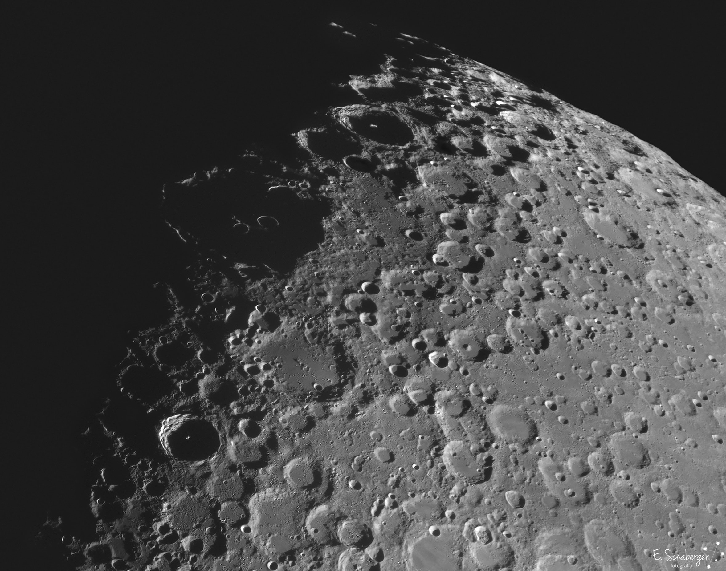 South is up in this dramatic telescopic view of the lunar terminator and the Moon's rugged southern highlands. The lunar landscape was captured on July 7 with the moon at its first quarter phase. The Sun shines at a low angle from the right as dawn comes to the region's young and old craters Tycho and Clavius. About 100 million years young, Tycho is the sharp-walled 85 kilometer diameter crater below and left of center. Its 2 kilometer tall central peak and far crater wall reflect bright sunlight, Its smooth floor lies in dark shadow. Debris ejected during the impact that created Tycho make it the stand out lunar crater when the Moon is near full though. They produce a highly visible radiating system of light streaks or rays that extend across much of the lunar near side. In fact, some of the material collected at the Apollo 17 landing site, about 2,000 kilometers away, likely originated from the Tycho impact.  One of the oldest and largest craters on the Moon's near side, 225 kilometer diameter Clavius is due south (above) of Tycho. Clavius crater's own ray system resulting from its original impact event would have faded long ago. The old crater's worn walls and smooth floor are now overlayed by newer smaller craters from impacts that occurred after Clavius was formed. Reaching above the older crater, tops of the newer crater walls reflect this dawn's early light to create narrow shining arcs within a shadowed Clavius.