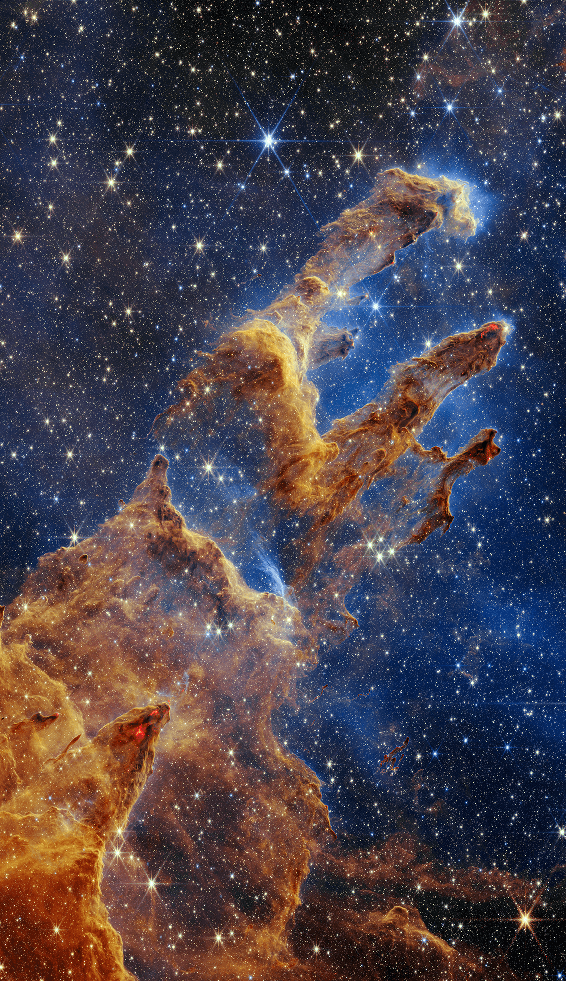 A now famous picture from the Hubble Space Telescope featured these star forming columns of cold gas and dust light-years long inside M16, the Eagle Nebula, dubbed the Pillars of Creation. This James Webb Space Telescope NIRCam image expands Hubble's exploration of that region in greater detail and depth inside the iconic stellar nursery. Particularly stunning in Webb's near infrared view is the telltale reddish emission from knots of material undergoing gravitational collapse to form stars within the natal clouds. The Eagle Nebula is some 6,500 light-years distant. The larger bright emission nebula is itself an easy target for binoculars or small telescopes. M16 lies along the plane of our Milky Way galaxy in a nebula rich part of the sky, toward the split constellation Serpens Cauda (the tail of the snake).