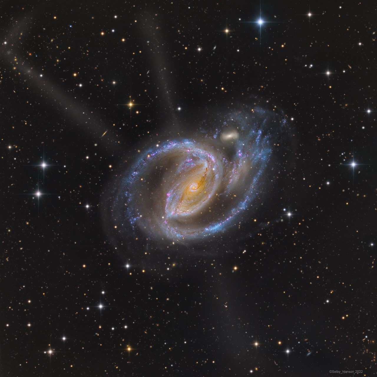 Spiral galaxy NGC 1097 shines in southern skies, about 45 million light-years away in the heated constellation Fornax. Its blue spiral arms are mottled with pinkish star forming regions in this colorful galaxy portrait. They seem to have wrapped around a small companion galaxy above and right of center, about 40,000 light-years from the spiral's luminous core. That's not NGC 1097's only peculiar feature, though. This very deep exposure hints of faint, mysterious jets, seen to extend well beyond the bluish arms. In fact, four faint jets are ultimately recognized in optical images of NGC 1097. The jets trace an X centered on the galaxy's nucleus, but probably don't originate there. Instead, they could be fossil star streams, trails left over from the capture and disruption of a much smaller galaxy in the large spiral's ancient past. A Seyfert galaxy, NGC 1097's nucleus also harbors a supermassive black hole.
