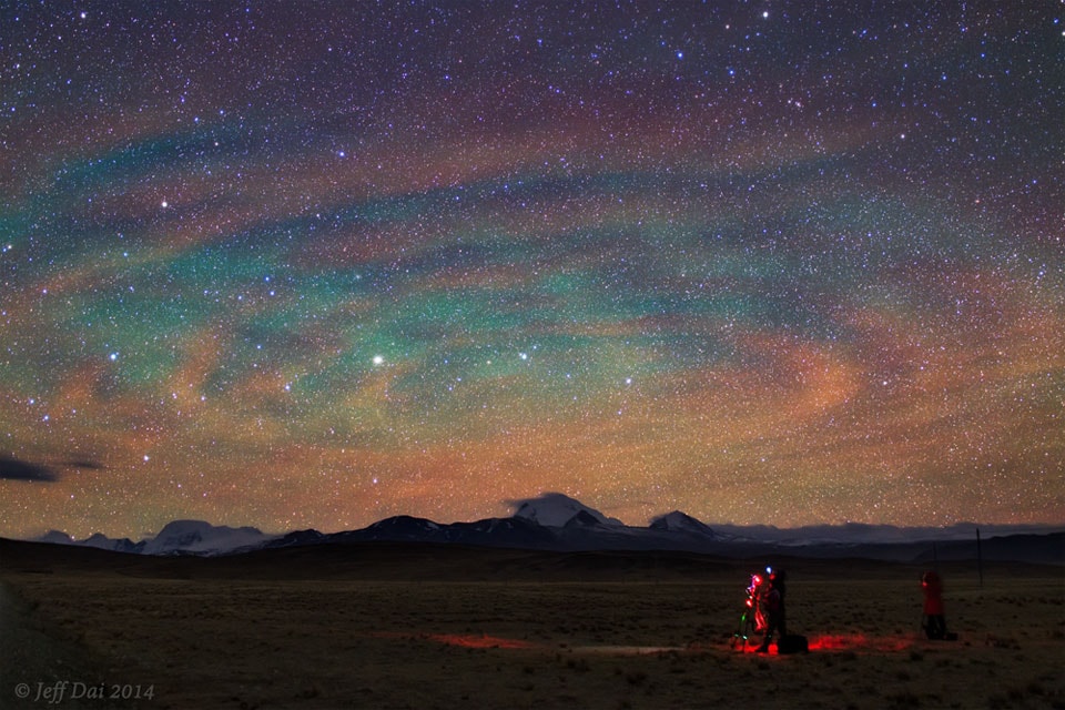 Why would the sky look like a giant target? Airglow. Following a giant thunderstorm over Bangladesh in late April, giant circular ripples of glowing air appeared over Tibet, China, as pictured here. The unusual pattern is created by atmospheric gravity waves, waves of alternating air pressure that can grow with height as the air thins, in this case about 90-kilometers up.  Unlike auroras powered by collisions with energetic charged particles and seen at high latitudes, airglow is due to chemiluminescence, the production of light in a chemical reaction.  More typically seen near the horizon, airglow keeps the night sky from ever being completely dark.