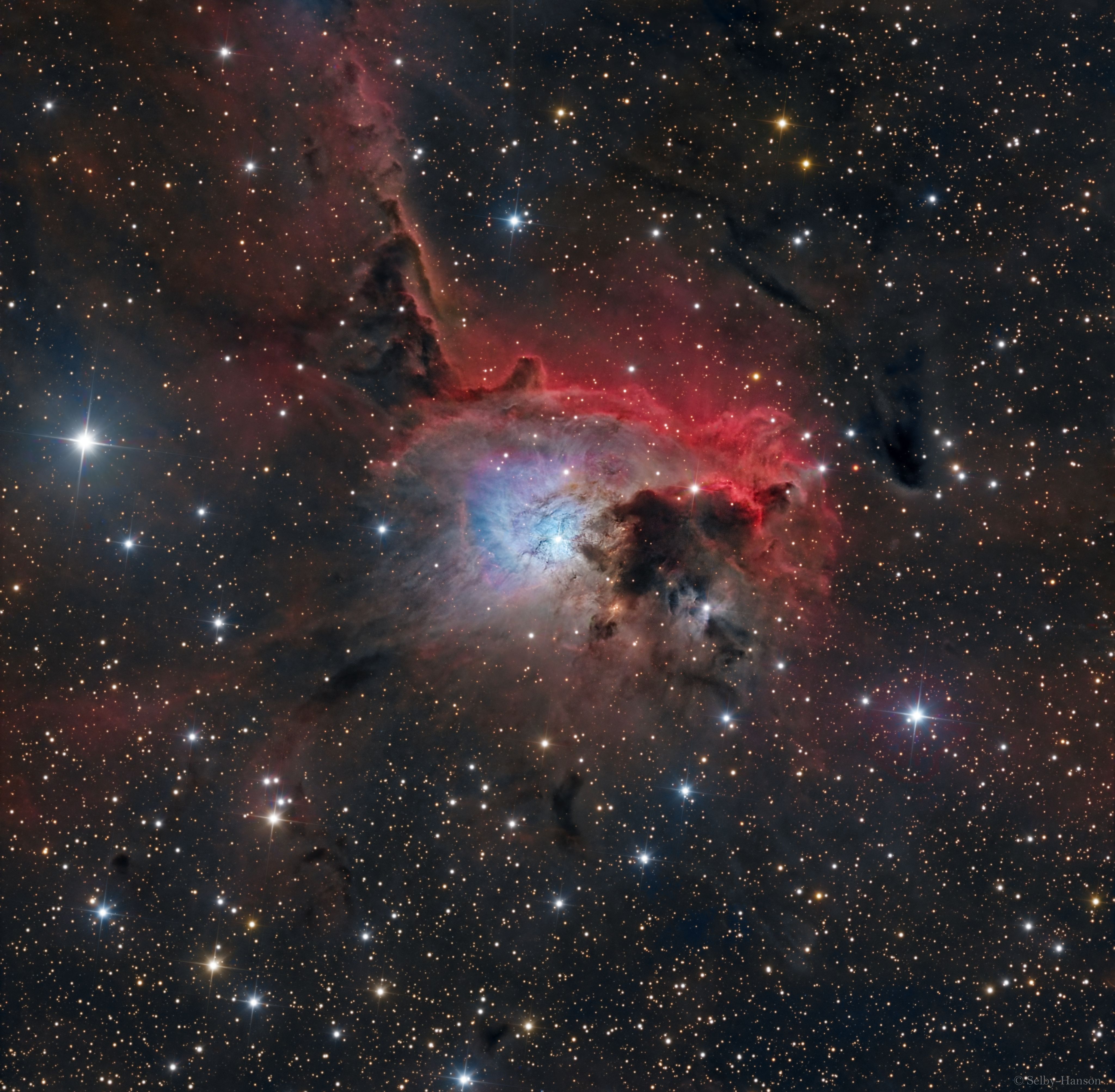 Centered in this colorful cosmic canvas, NGC 2626 is a beautiful, bright, blue reflection nebula in the southern Milky Way. Next to an obscuring dust cloud and surrounded by reddish hydrogen emission from large H II region RCW 27 it lies within a complex of dusty molecular clouds known as the Vela Molecular Ridge. NGC 2626 is itself a cloud of interstellar dust reflecting blue light from the young hot embedded star visible within the nebula. But astronomical explorations reveal many other young stars and associated nebulae in the star-forming region. NGC 2626 is about 3,200 light-years away. At that distance this telescopic field of view would span about 30 light-years along the Vela Molecular Ridge.