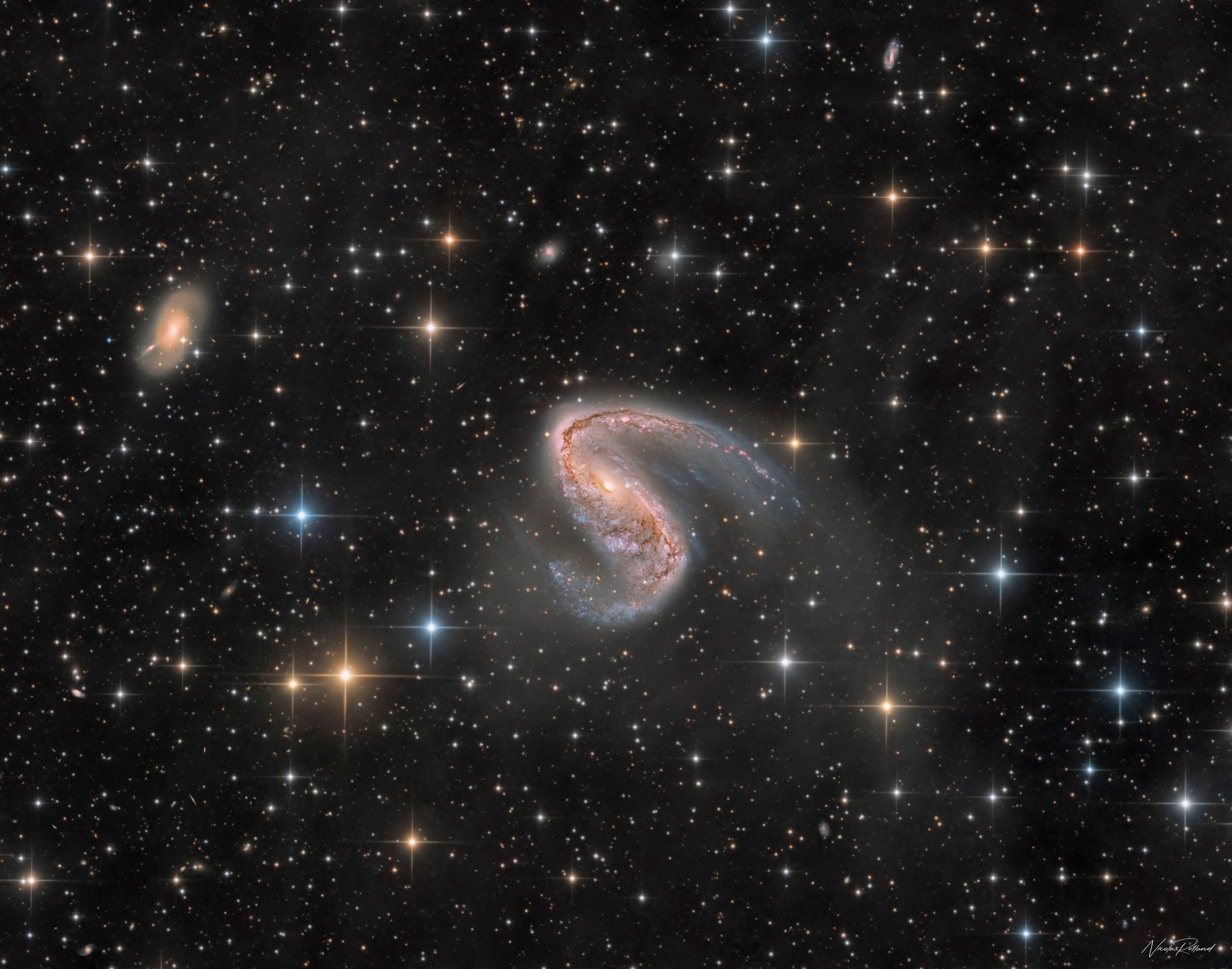 Distorted galaxy NGC 2442 can be found in the southern constellation of the flying fish, (Piscis) Volans. Located about 50 million light-years away, the galaxy's two spiral arms extending from a pronounced central bar give it a hook-shaped appearance in this deep colorful image, with spiky foreground stars scattered across the telescopic field of view. The image also reveals the distant galaxy's obscuring dust lanes, young blue star clusters and reddish star forming regions surrounding a core of yellowish light from an older population of stars. But the star forming regions seem more concentrated along the drawn-out (upper right) spiral arm. The distorted structure is likely the result of an ancient close encounter with the smaller galaxy seen near the top left of the frame. The two interacting galaxies are separated by about 150,000 light-years at the estimated distance of NGC 2442.