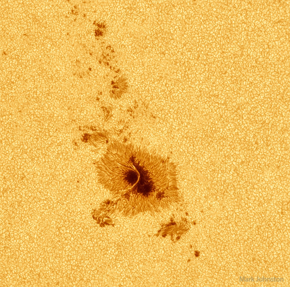 Why would a small part of the Sun appear slightly dark?  Visible is a close-up picture of sunspots, depressions on the Sun's surface that are slightly cooler and less bright than the rest of the Sun.  The Sun's complex magnetic field creates these cool regions by inhibiting hot material from entering the spots.  Sunspots can be larger than the Earth and typically last for about a week.  Part of active region AR 3297 crossing the Sun in early May, the large lower sunspot is spanned by an impressive light bridge of hot and suspended solar gas.  This high-resolution picture also shows clearly that the Sun's surface is a bubbling carpet of separate cells of hot gas. These cells are known as granules.  A solar granule is about 1000 kilometers across and lasts for only about 15 minutes.    Your Sky Surprise: What picture did APOD feature on your birthday? (post 1995)