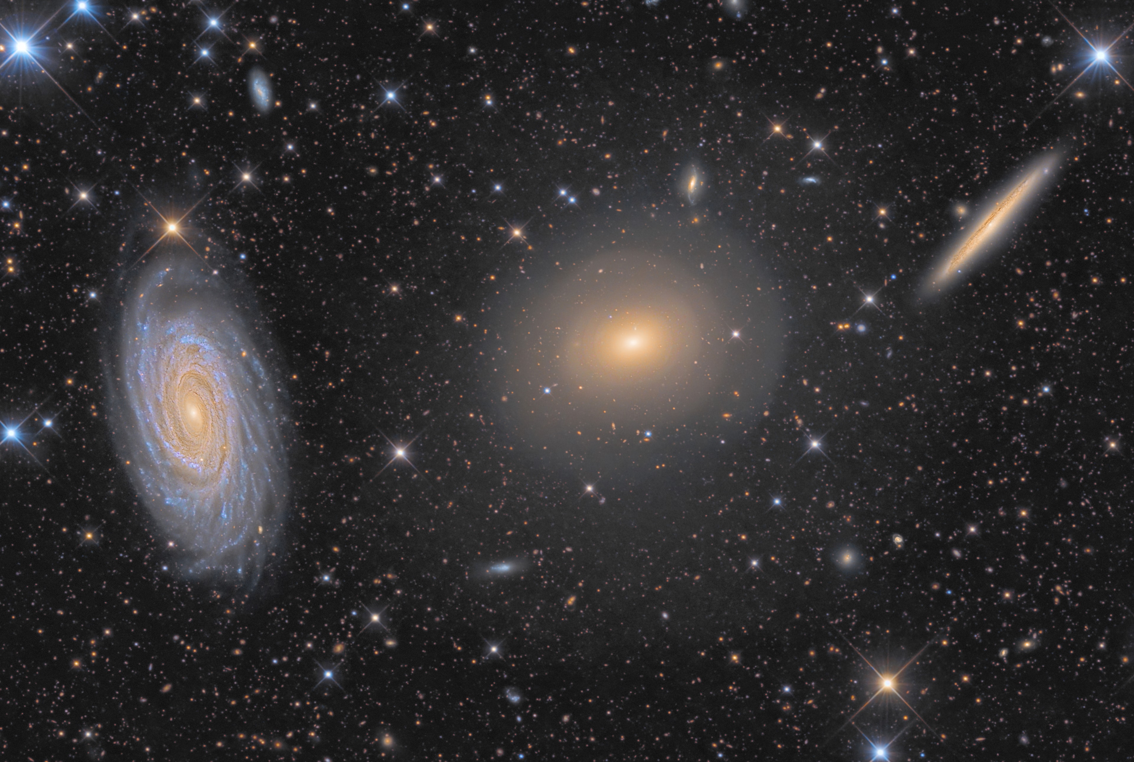 This tantalizing trio of galaxies sometimes called the Draco Group, is located in the northern constellation of (you guessed it) Draco, the Dragon. From left to right are face-on spiral NGC 5985, elliptical galaxy NGC 5982, and edge-on spiral NGC 5981, all found within this single telescopic field of view that spans a little more than the width of the full moon. While the group is far too small to be a galaxy cluster, and has not been catalogued as a compact galaxy group, the three galaxies all do lie roughly 100 million light-years from planet Earth. Not as well known as other tight groupings of galaxies, the contrast in visual appearance still makes this triplet an attractive subject for astroimagers. On close examination with spectrographs, the bright core of striking spiral NGC 5985 shows prominent emission in specific wavelengths of light, prompting astronomers to classify it as a Seyfert, a type of active galaxy. This impressively deep exposure hints at a faint dim halo along with sharp-edged shells surrounding elliptical NGC 5982, evidence of past galactic mergers. It also reveals many even more distant background galaxies.