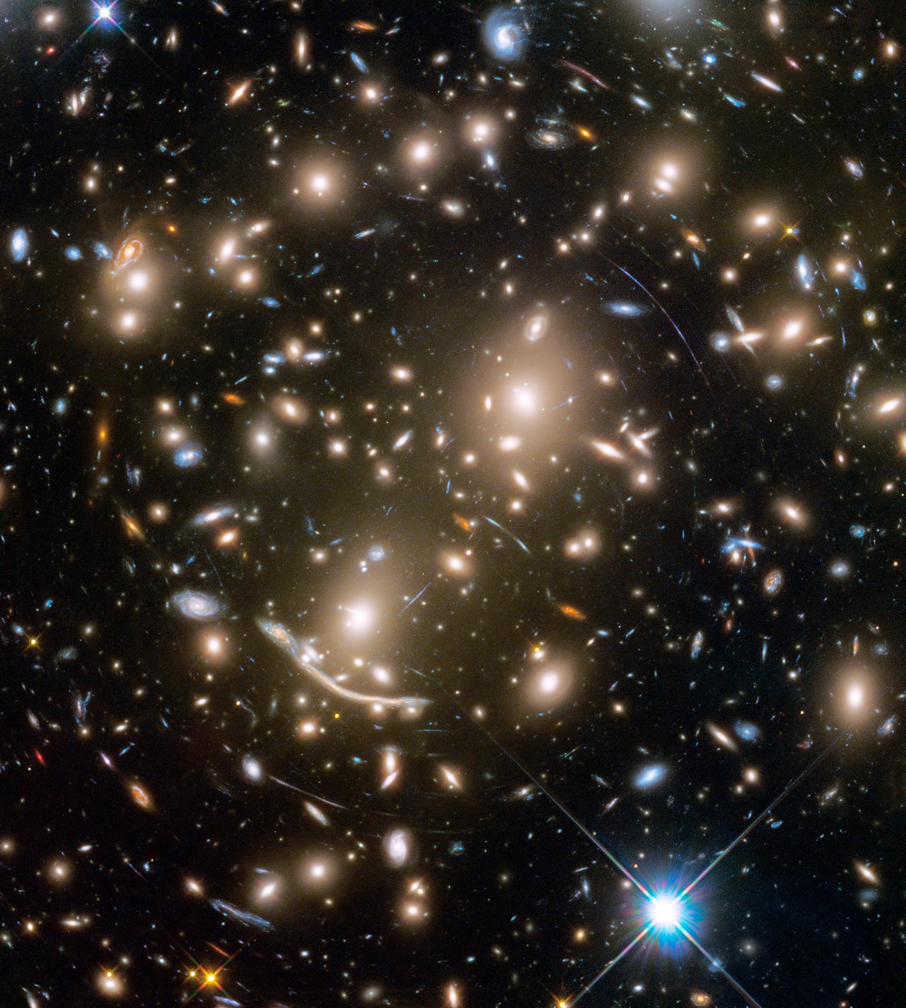 Some 4 billion light-years away, massive galaxy cluster Abell 370 is captured in this sharp Hubble Space Telescope snapshot. The cluster of galaxies only appears to be dominated by two giant elliptical galaxies and infested with faint arcs. In reality, the fainter, scattered bluish arcs, along with the dramatic dragon arc below and left of center, are images of galaxies that lie far beyond Abell 370. About twice as distant, their otherwise undetected light is magnified and distorted by the cluster's enormous gravitational mass, overwhelmingly dominated by unseen dark matter. Providing a tantalizing glimpse of galaxies in the early universe, the effect is known as gravitational lensing. A consequence of warped spacetime, lensing was predicted by Einstein almost a century ago. Far beyond the spiky foreground Milky Way star at lower right, Abell 370 is seen toward the constellation Cetus, the Sea Monster. It was the last of six galaxy clusters imaged in the Frontier Fields project.