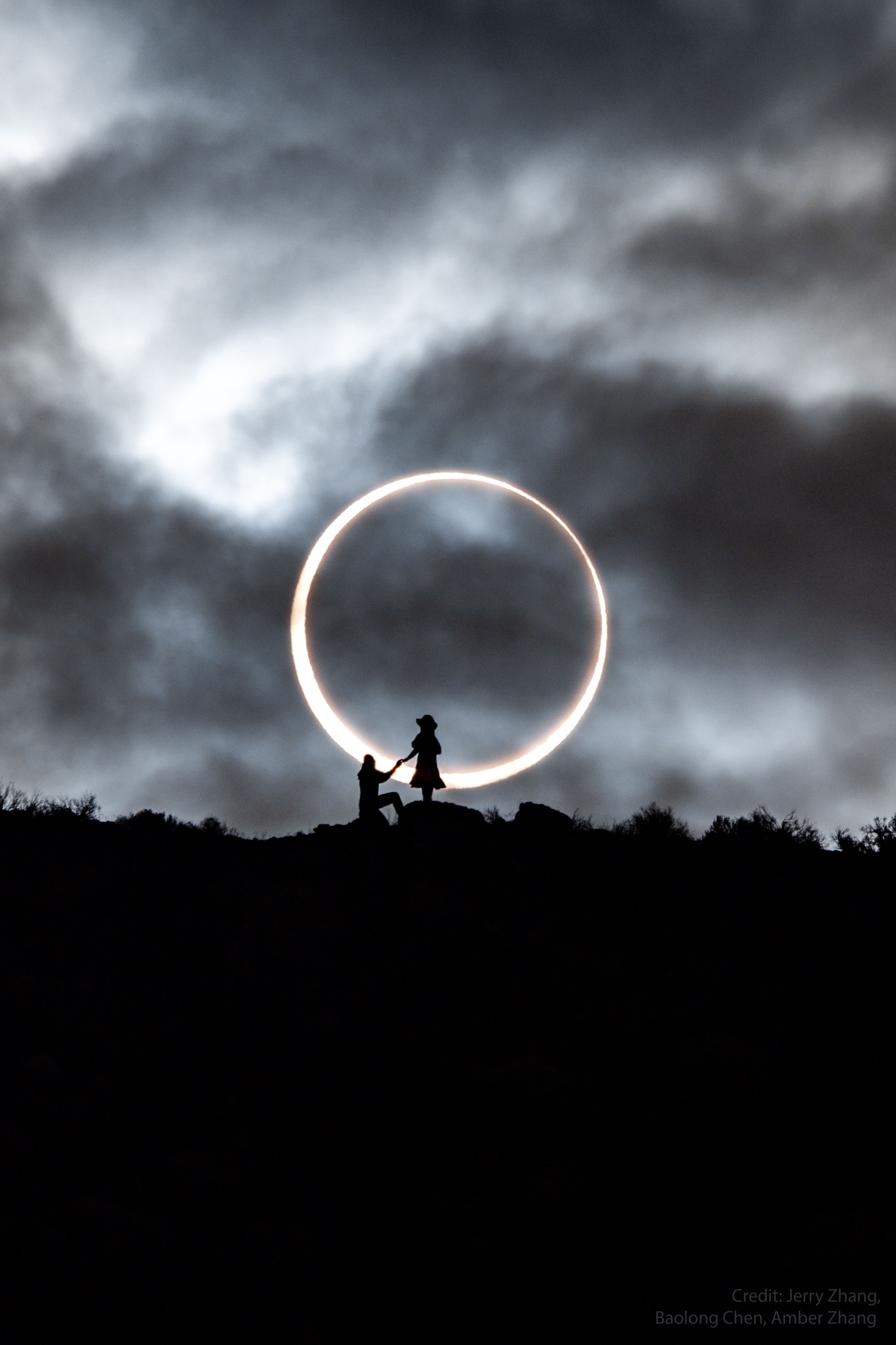 She knew everything but the question. She was well aware that there would be a complete annular eclipse of the Sun visible from their driving destination: Lake Abert in Oregon.  She knew that the next ring-of-fire eclipse would occur in the USA only in 16 more years, making this a rare photographic opportunity.  She was comfortable with the plan: that she and her boyfriend would appear in front of the eclipse in silhouette, sometimes alone, and sometimes together.  She knew that the annular phase of this eclipse would last only a few minutes and she helped in the many hours of planning.  She could see their friend who set up the camera about 400 meters away at the bottom of a ridge.  What she didn't know was the question she would be asked. But she did know the answer: "yes".   Album: Selected eclipse images sent in to APOD