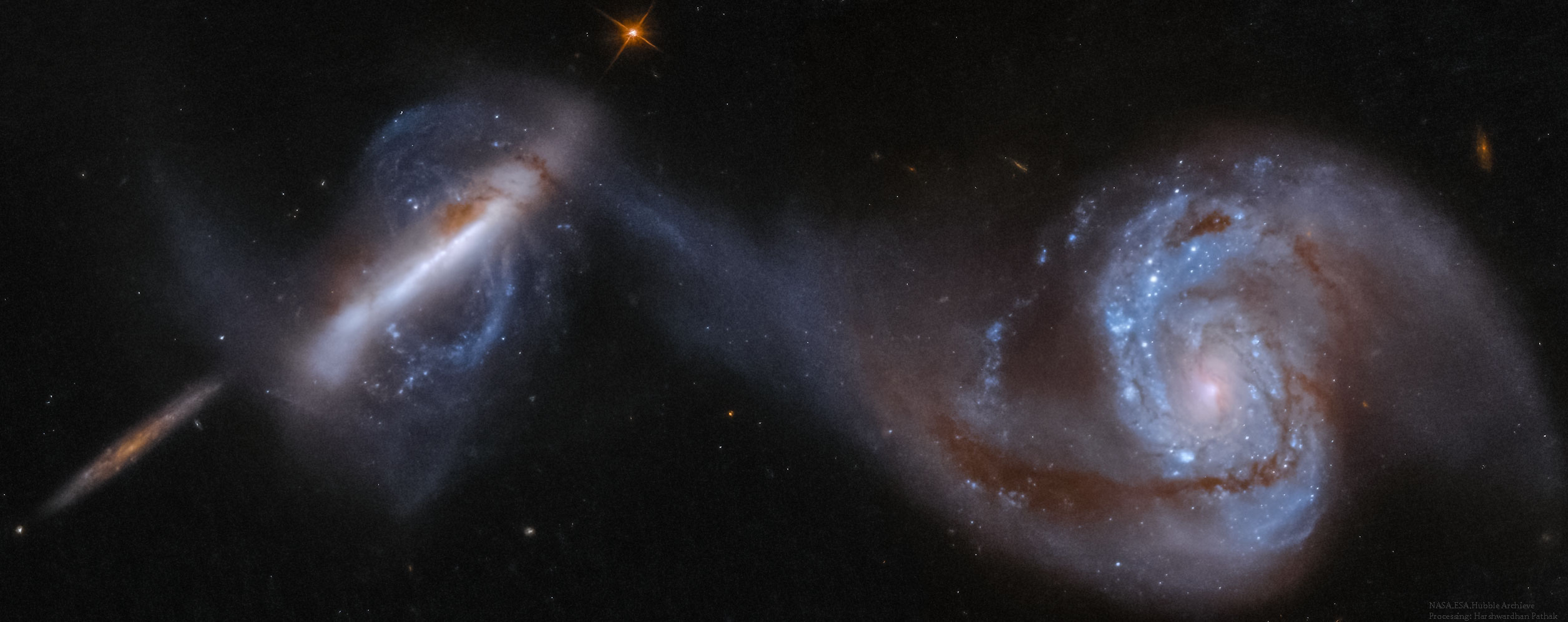 This dance is to the death.  As these two large galaxies duel, a cosmic bridge of stars, gas, and dust currently stretches over 75,000 light-years and joins them.  The bridge itself is strong evidence that these two immense star systems have passed close to each other and experienced violent tides induced by mutual gravity. As further evidence, the face-on spiral galaxy on the right, also known as NGC 3808A, exhibits many young blue star clusters produced in a burst of star formation. The twisted edge-on spiral on the left (NGC 3808B) seems to be wrapped in the material bridging the galaxies and surrounded by a curious polar ring. Together, the system is known as Arp 87. While such interactions are drawn out over billions of years, repeated close passages will ultimately create one merged galaxy. Although this scenario does look unusual, galactic mergers are thought to be common, with Arp 87 representing a stage in this inevitable process. The Arp 87 dancing pair are about 300 million light-years distant toward the constellation of the Lion (Leo). The prominent edge-on spiral galaxy at the far left appears to be a more distant background galaxy and not involved in the on-going merger.