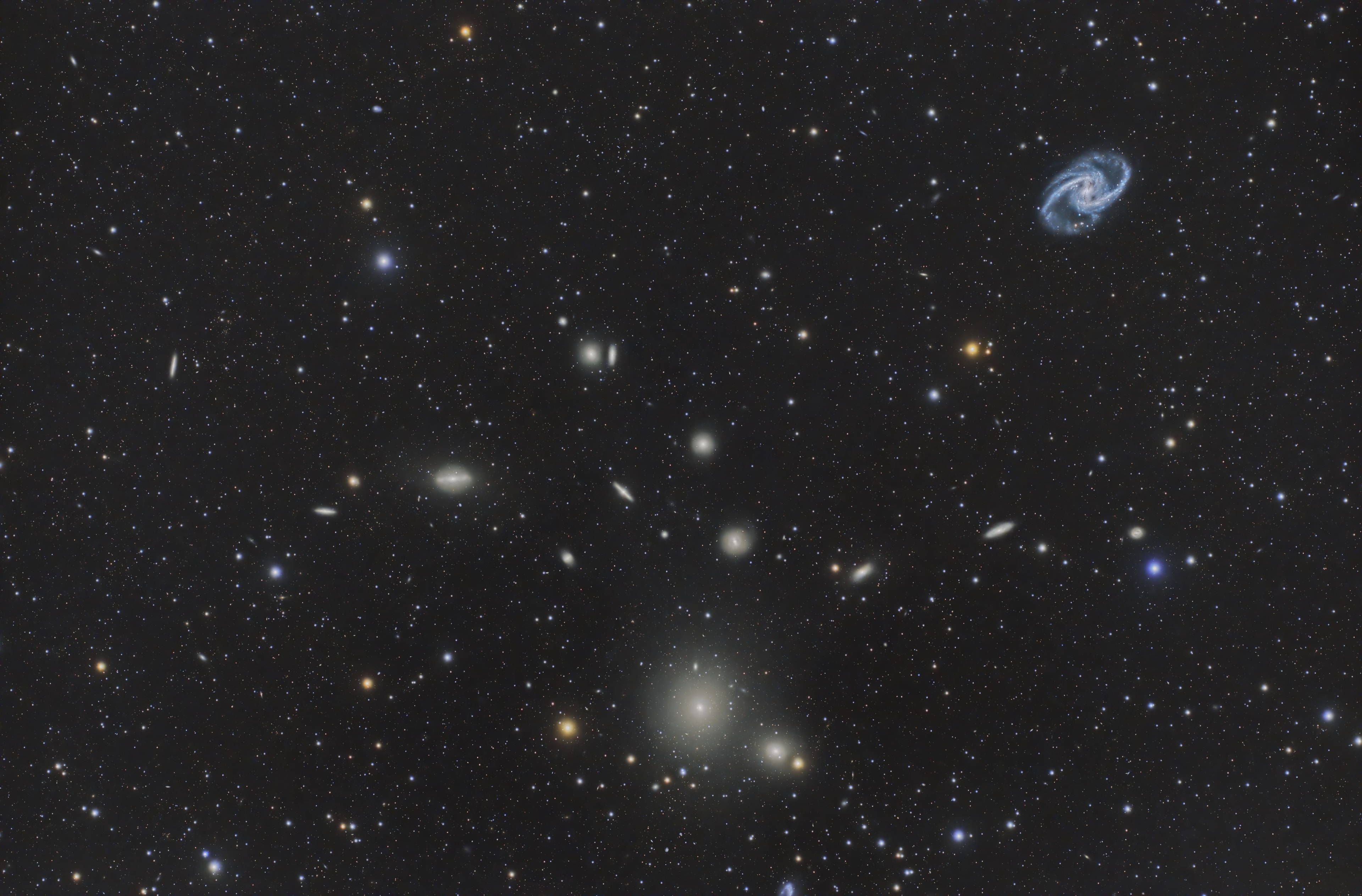 Named for the southern constellation toward which most of its galaxies can be found, the Fornax Cluster is one of the closest clusters of galaxies. About 62 million light-years away, it's over 20 times more distant than our neighboring Andromeda Galaxy, but only about 10 percent farther along than the better known and more populated Virgo Galaxy Cluster. Seen across this three degree wide field-of-view, almost every yellowish splotch on the image is an elliptical galaxy in the Fornax cluster. Elliptical galaxies NGC 1399 and NGC 1404 are the dominant, bright cluster members toward the bottom center. A standout, large barred spiral galaxy, NGC 1365, is visible on the upper right as a prominent Fornax cluster member.