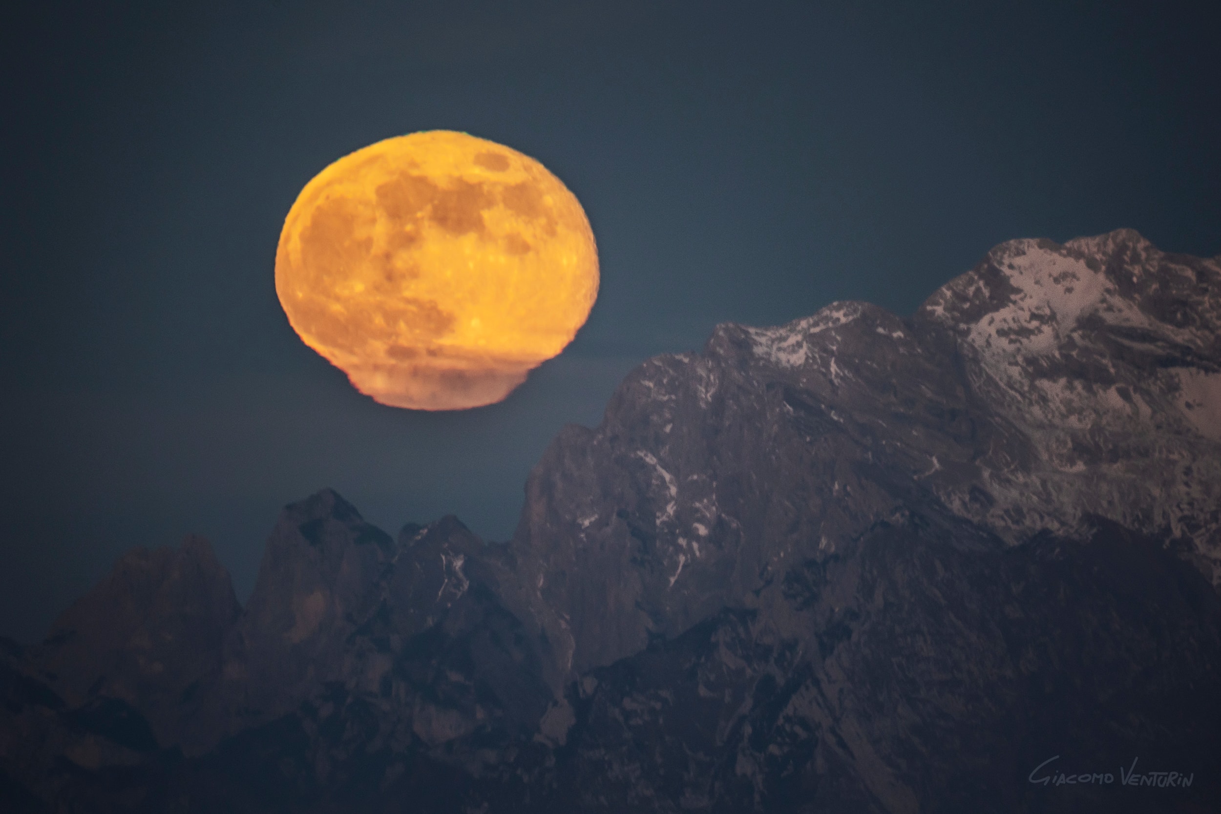 Known to some in the northern hemisphere as December's Cold Moon or the Long Night Moon, the last full moon of 2023 is rising in this surreal mountain and skyscape. The Daliesque scene was captured in a single exposure with a camera and long telephoto lens near Monte Grappa, Italy. The full moon is not melting, though. Its stretched and distorted appearance near the horizon is caused as refraction along the line of sight changes and creates shifting images or mirages of the bright lunar disk. The changes in atmospheric refraction correspond to atmospheric layers with sharply different temperatures and densities. Other effects of atmospheric refraction produced by the long sight-line to this full moon rising include the thin red rim seen faintly on the distorted lower edge of the Moon and a thin green rim along the top.