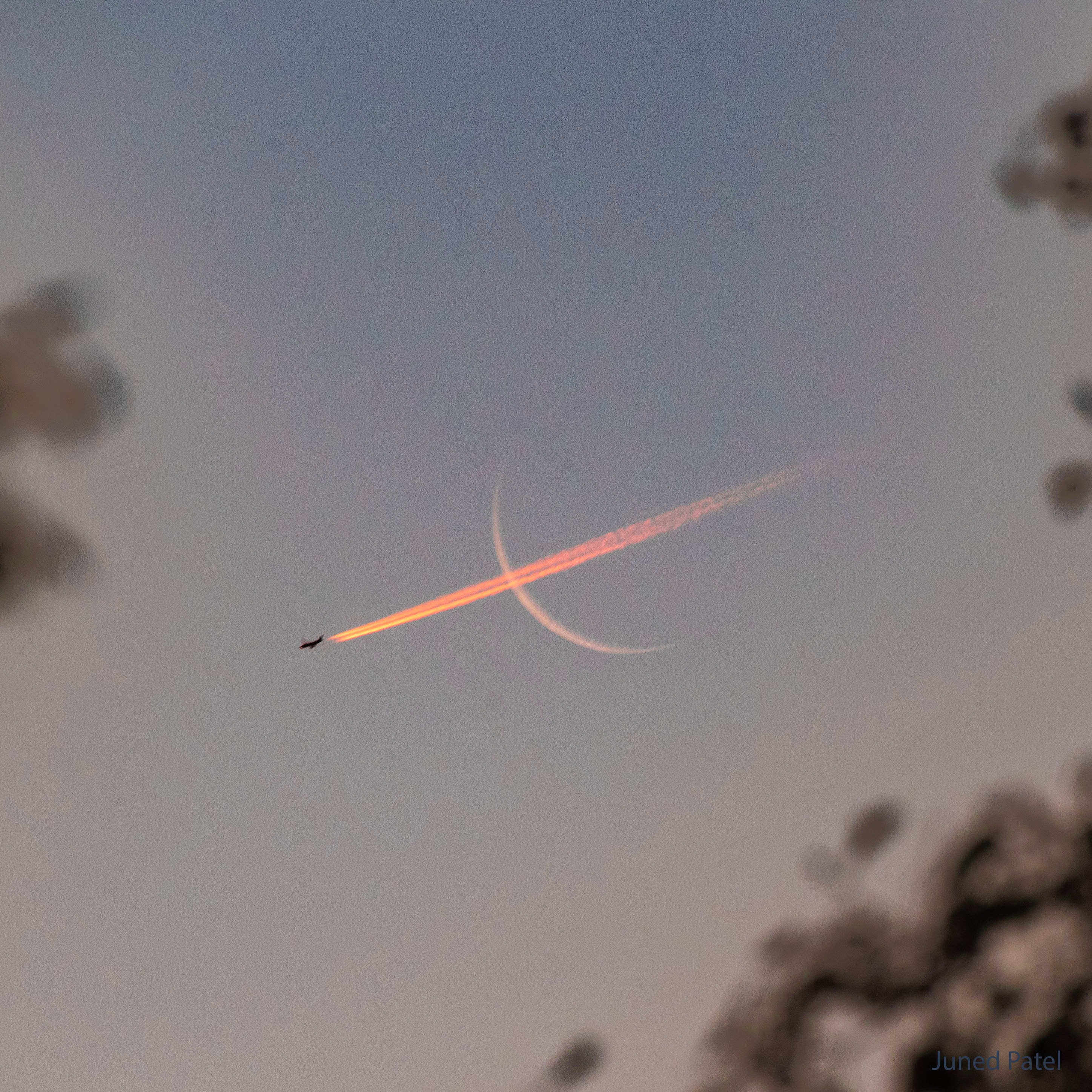 No, the Moon is not a bow, and no, it did not shoot out a plane like an arrow. What is pictured is a chance superposition.  The plane's contrail would normally appear white, but the large volume of air toward the rising Sun preferentially knocked away blue light, not only making the sky blue, but giving the reflected trail a bright red hue.  Far in the distance, well behind the plane, the crescent Moon also appears slightly reddened. Captured early last month from Bolton, UK, the featured image was taken so soon after sunrise that the plane was sunlit from below, as was its contrail.  Within minutes, unfortunately, the impromptu sky show ended.  The plane moved out of sight.  The Moon kept rising but became harder to see through a brightening sky.  And the contrail gradually dispersed.