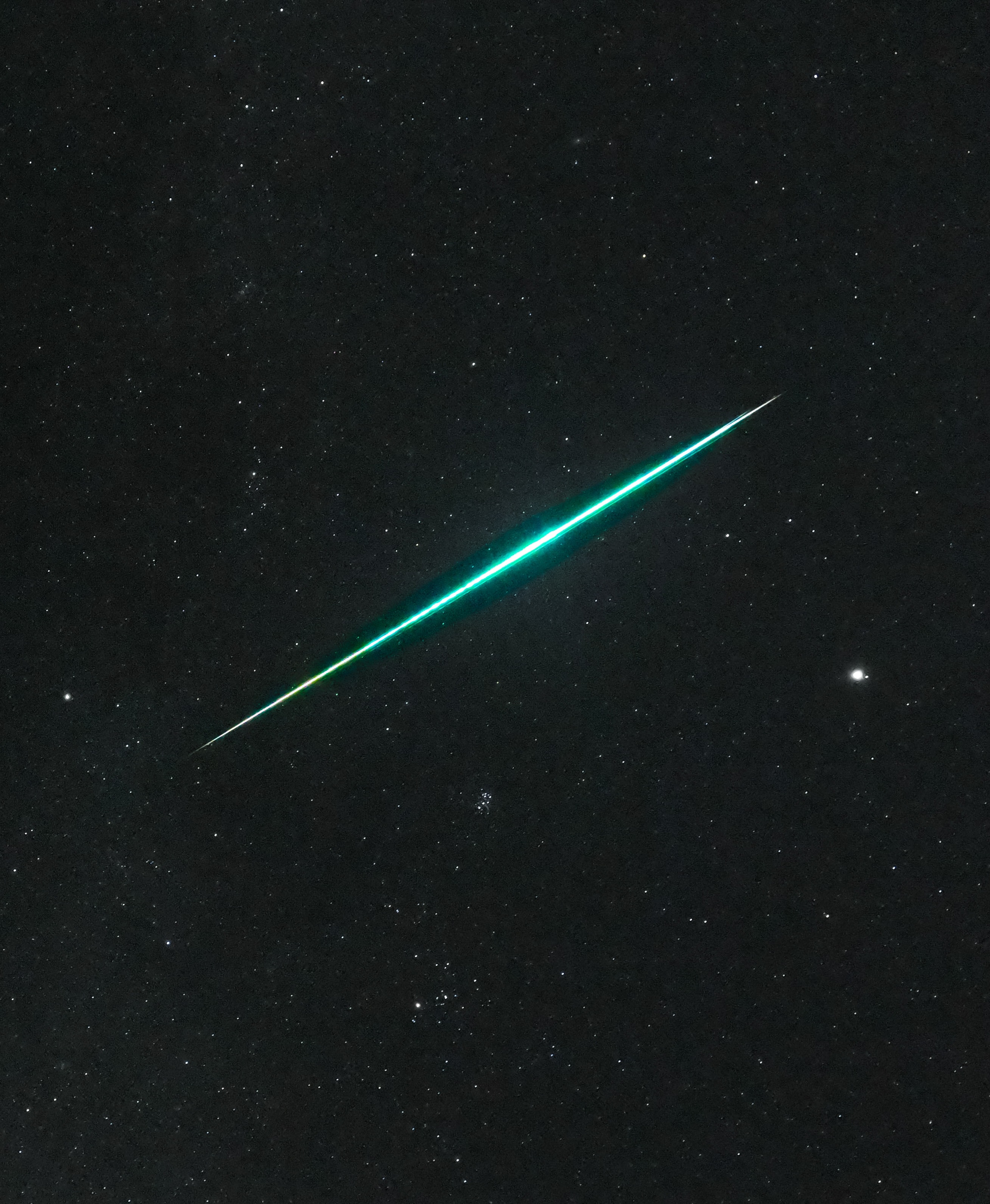 For a brief moment, this brilliant fireball meteor outshone Jupiter in planet Earth's night. The serendipitous image was captured while hunting meteors under cold Canadian skies with a camera in timelapse mode on December 14, near the peak of the Geminid meteor shower. The Geminid meteor shower, asteroid 3200 Phaethon's annual gift, always arrives in December. Dust shed along the orbit of the mysterious asteroid causes the meteor streaks, as the vaporizing grains plow through our fair planet's upper atmosphere at 22 kilometers per second. Of course Geminid shower meteors appear to radiate from a point in the constellation of the Twins. That's below and left of this frame. With bright Jupiter on the right, also in the December night skyview are the Pleiades and Hyades star clusters.