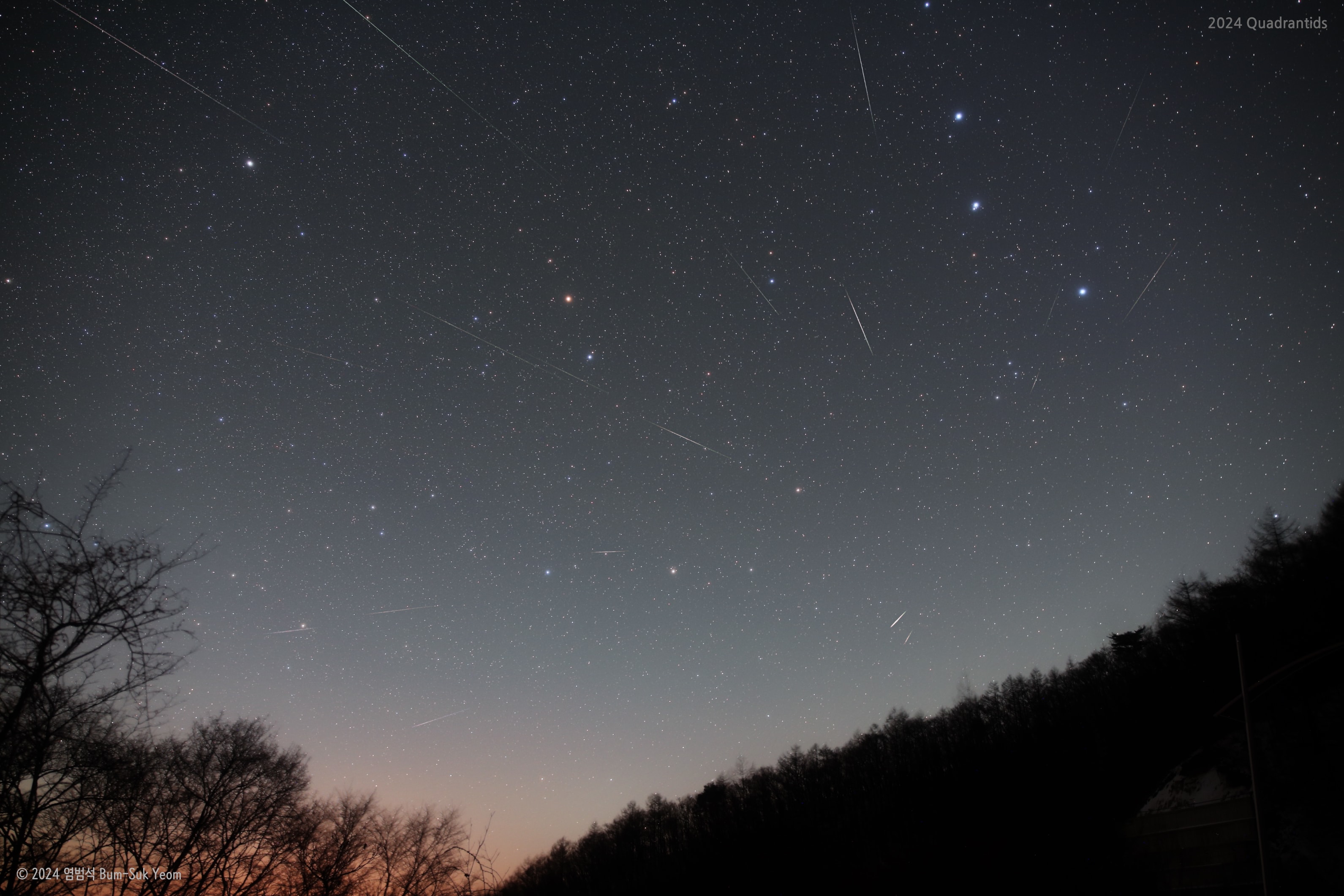 Named for a forgotten constellation, the Quadrantid Meteor Shower puts on an annual show for planet Earth's northern hemisphere skygazers. The shower's radiant on the sky lies within the old, astronomically obsolete constellation Quadrans Muralis. That location is not far from the Big Dipper asterism, known to some as the Plough, at the boundaries of the modern constellations Bootes and Draco. The Big Dipper "handle" stars are near the upper right corner in this frame, with the meteor shower radiant just below. North star Polaris is toward the top left. Pointing back toward the radiant, Quadrantid meteors streak through the night in this skyscape from Jangsu, South Korea. The composite image was recorded in the hours around the shower's peak on January 4, 2024. A likely source of the dust stream that produces Quadrantid meteors was identified in 2003 as an asteroid.