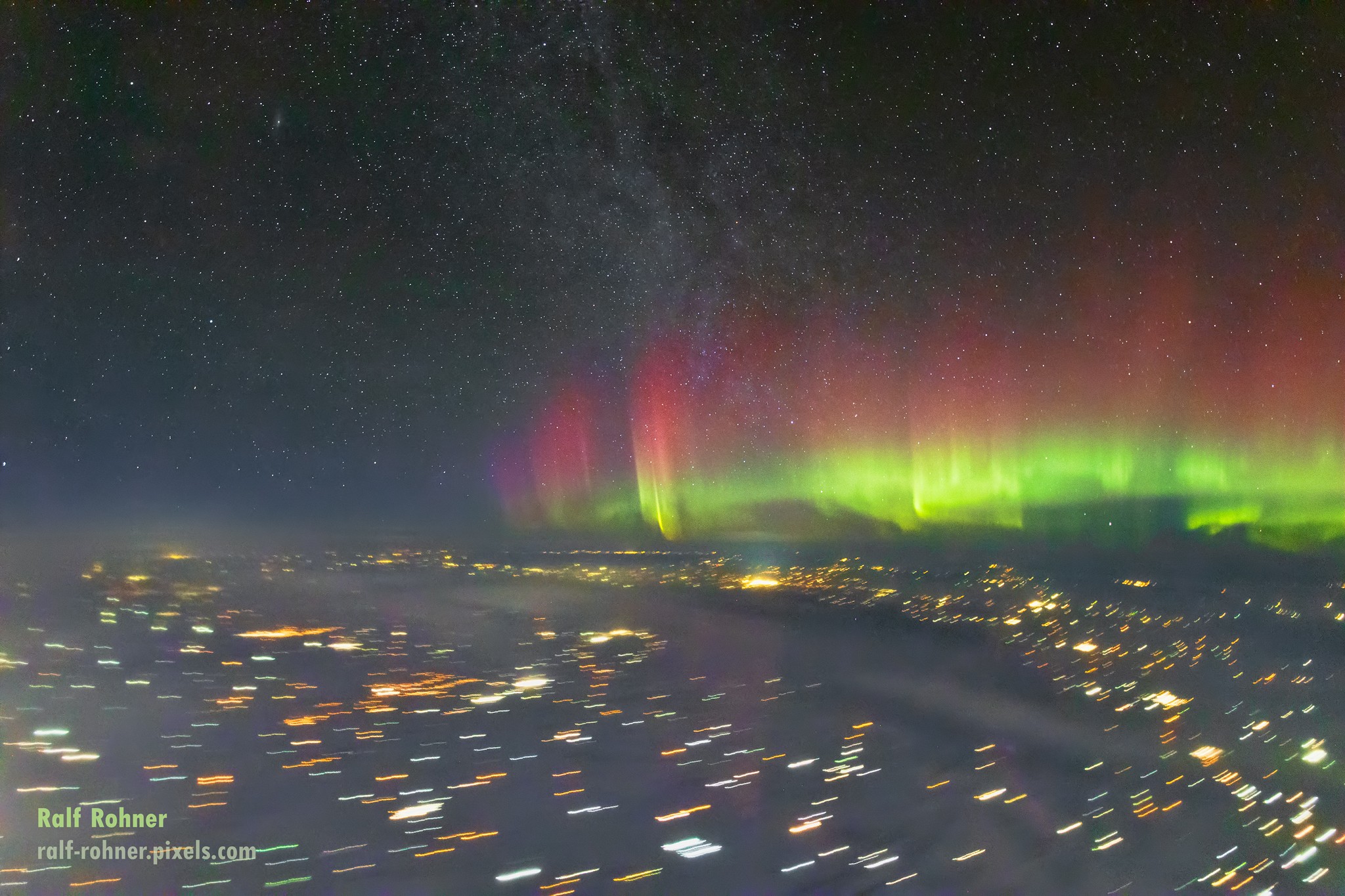 Northern lights shine in this night skyview from planet Earth's stratosphere, captured on January 15. The single, 5 second exposure was made with a hand-held camera on board an aircraft above Winnipeg, Canada. During the exposure, terrestrial lights below leave colorful trails along the direction of motion of the speeding aircraft. Above the more distant horizon, energetic particles accelerated along Earth's magnetic field at the planet's polar regions excite atomic oxygen to create the shimmering display of Aurora Borealis. The aurora's characteristic greenish hue is generated at altitudes of 100-300 kilometers and red at even higher altitudes and lower atmospheric densities. The luminous glow of faint stars along the plane of our Milky Way galaxy arcs through the night, while the Andromeda galaxy extends this northern skyview to extragalactic space. A diffuse hint of Andromeda, the closest large spiral to the Milky Way, can just be seen to the upper left.