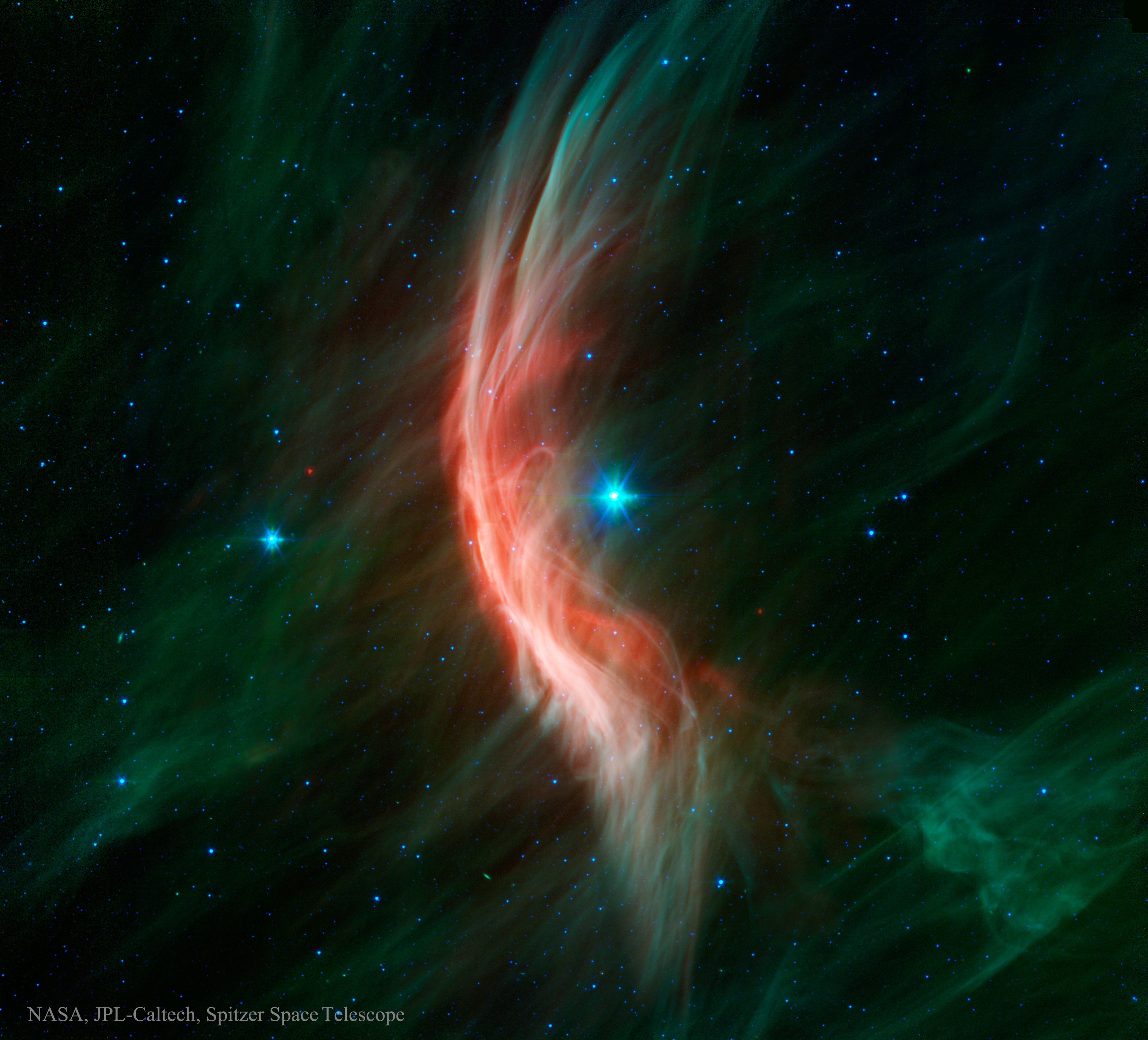 Like a ship plowing through cosmic seas, runaway star Zeta Ophiuchi produces the arcing interstellar bow wave or bow shock seen in this stunning infrared portrait. In the false-color view, bluish Zeta Oph, a star about 20 times more massive than the Sun, lies near the center of the frame, moving toward the left at 24 kilometers per second. Its strong stellar wind precedes it, compressing and heating the dusty interstellar material and shaping the curved shock front. What set this star in motion? Zeta Oph was likely once a member of a binary star system, its companion star was more massive and hence shorter lived. When the companion exploded as a supernova catastrophically losing mass, Zeta Oph was flung out of the system.  About 460 light-years away, Zeta Oph is 65,000 times more luminous than the Sun and would be one of the brighter stars in the sky if it weren't surrounded by obscuring dust. The image spans about 1.5 degrees or 12 light-years at the estimated distance of Zeta Ophiuchi. In January 2020, NASA placed the Spitzer Space Telescope in safe mode, ending its 16 successful years of exploring the cosmos.