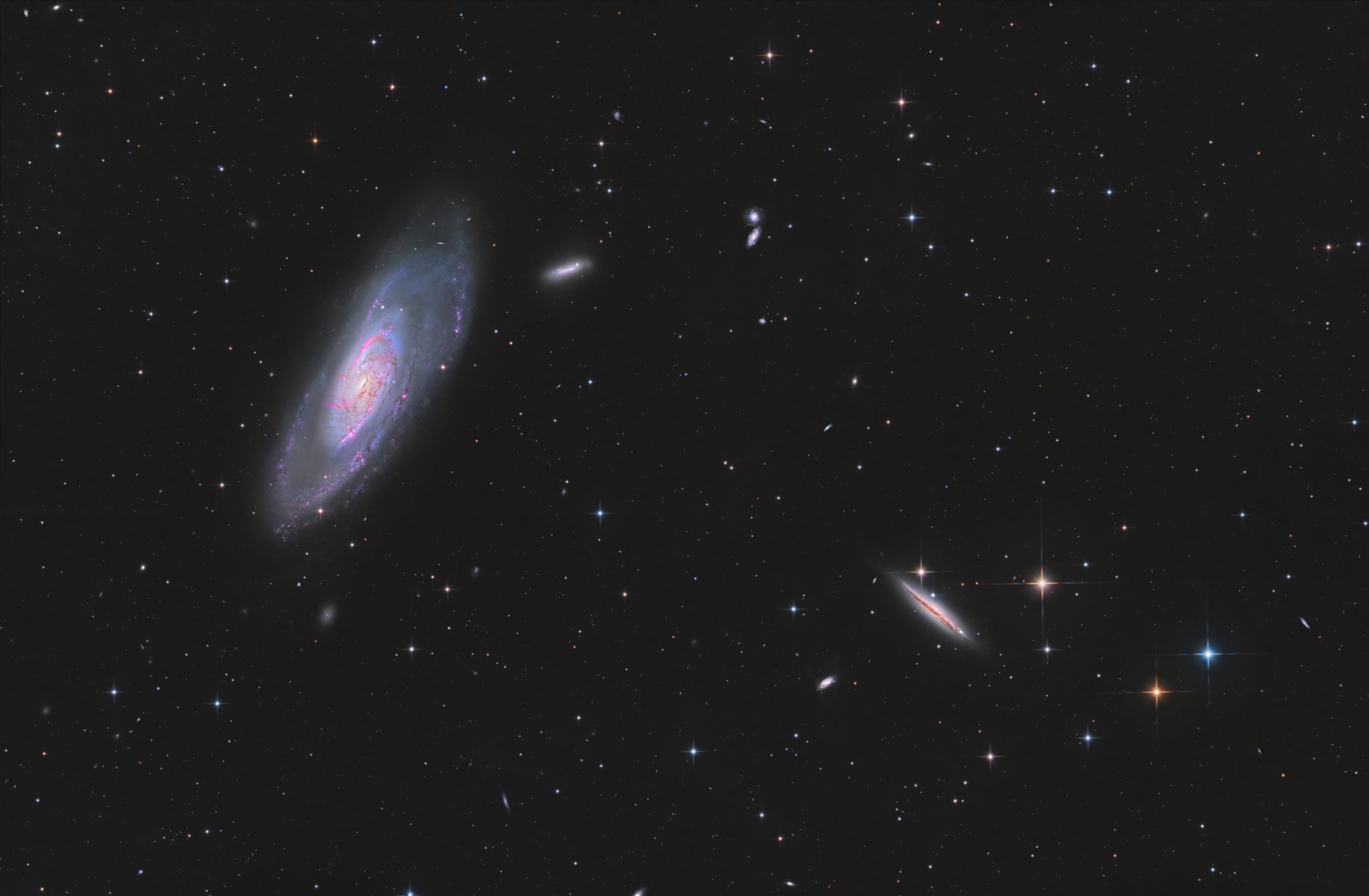 Big, bright, beautiful spiral, Messier 106 dominates this cosmic vista. The nearly two degree wide telescopic field of view looks toward the well-trained constellation Canes Venatici, near the handle of the Big Dipper. Also known as NGC 4258, M106 is about 80,000 light-years across and 23.5 million light-years away, the largest member of the Canes II galaxy group. For a far far away galaxy, the distance to M106 is well-known in part because it can be directly measured by tracking this galaxy's remarkable maser, or microwave laser emission. Very rare but naturally occurring, the maser emission is produced by water molecules in molecular clouds orbiting its active galactic nucleus. Another prominent spiral galaxy on the scene, viewed nearly edge-on, is NGC 4217 below and right of M106. The distance to NGC 4217 is much less well-known, estimated to be about 60 million light-years, but the bright spiky stars are in the foreground, well inside our own Milky Way galaxy.