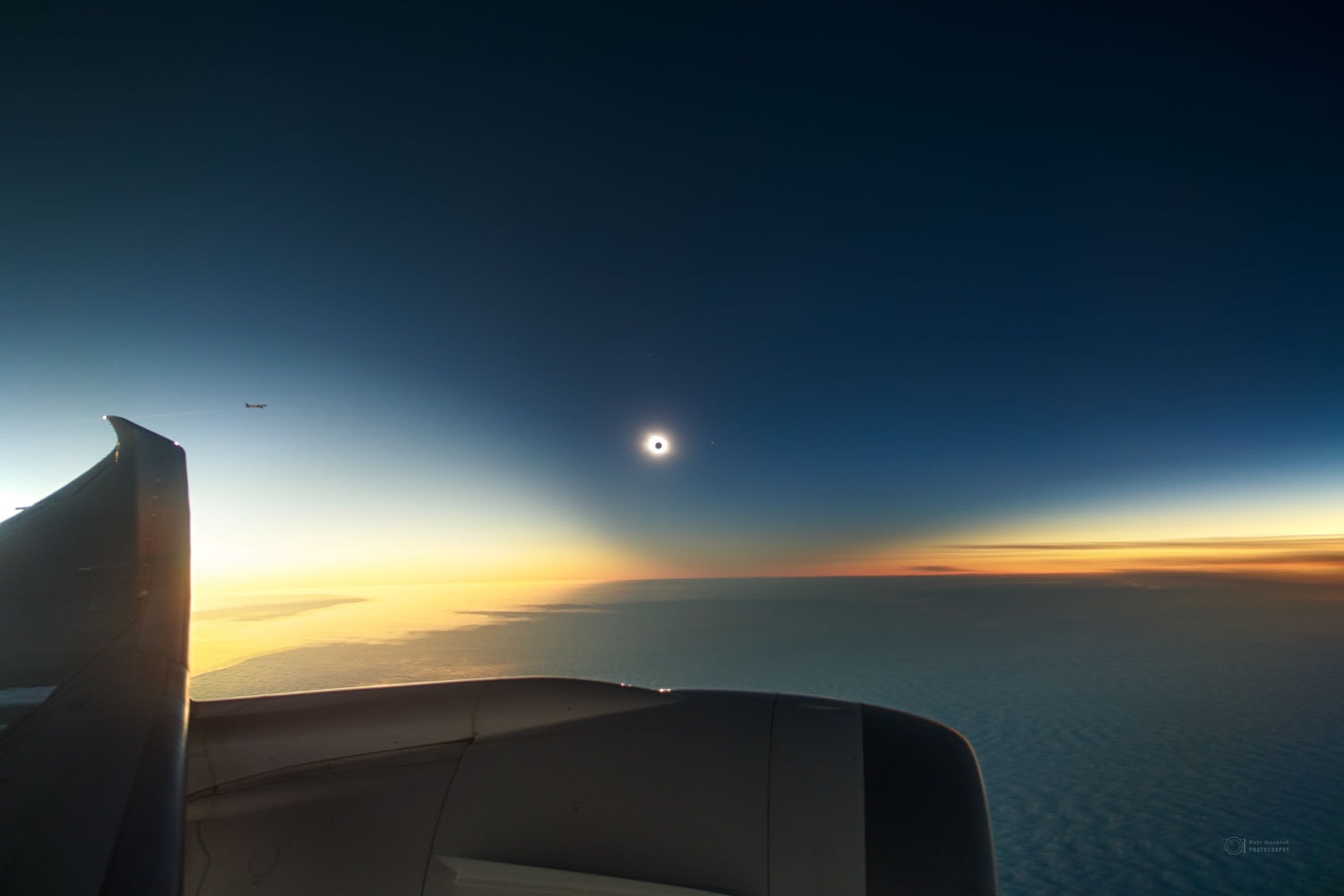 In late 2021 there was a total solar eclipse visible only at the end of the Earth.  To capture the unusual phenomenon, airplanes took flight below the clouded seascape of Southern Ocean. The featured image shows one relatively spectacular capture where the bright spot is the outer corona of the Sun and the eclipsing Moon is seen as the dark spot in the center.  A wing and engine of the airplane are visible across the left and bottom of the image, while another airplane observing the eclipse is visible on the far left. The dark area of the sky surrounding the eclipsed Sun is called a shadow cone. It is dark because you are looking down a long corridor of air shadowed by the Moon. A careful inspection of the eclipsed Sun will reveal the planet Mercury just to the right. You won't have to travel to the end of the Earth to see the next total solar eclipse. The total eclipse path will cross North America on 2024 April 8, just over one week from today.   NASA Coverage: Total Solar Eclipse of 2024 April 8