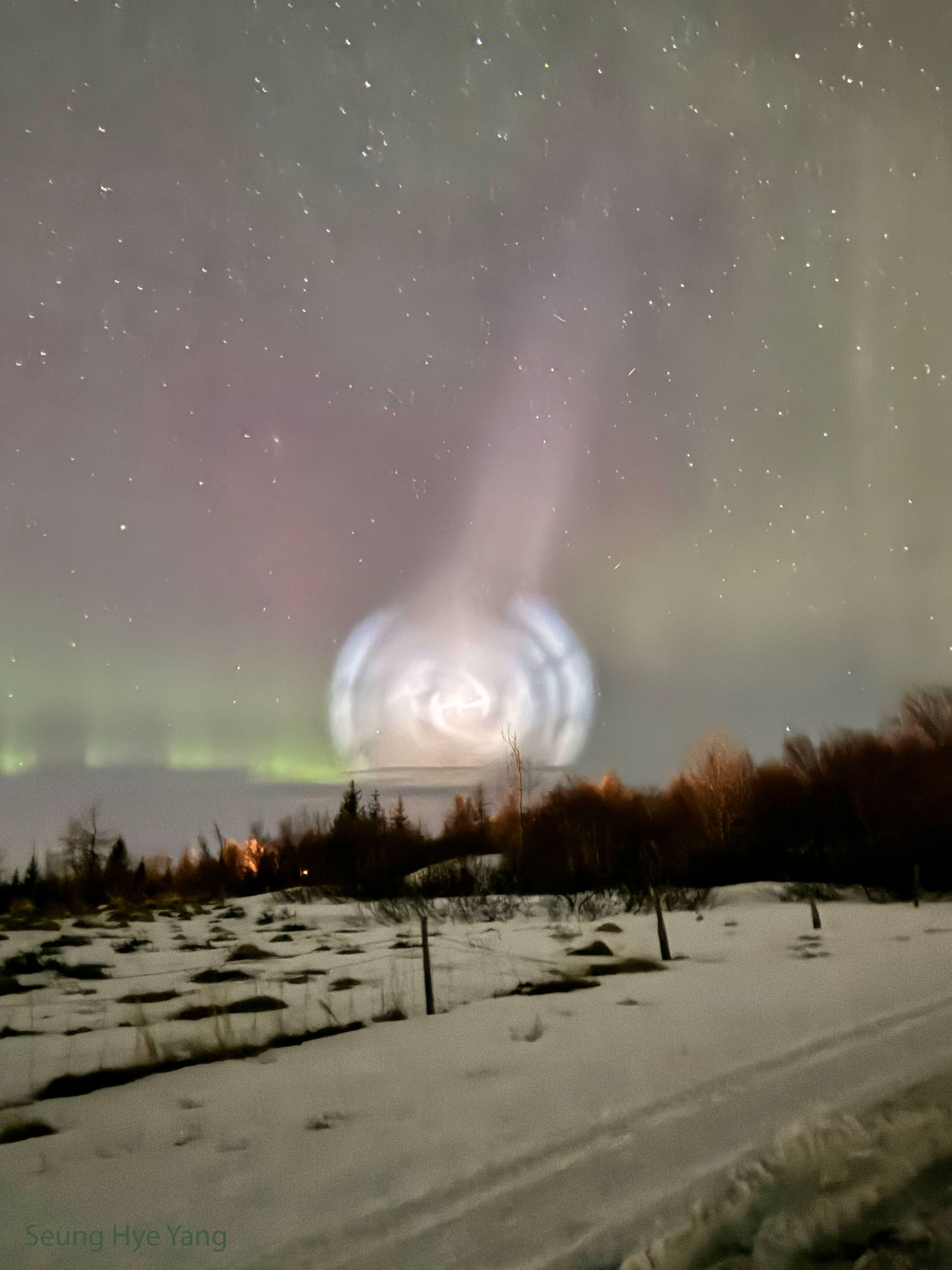 What's that over the horizon? What may look like a strangely nearby galaxy is actually a normal rocket's exhaust plume -- but unusually backlit.  Although the SpaceX Falcon 9 rocket was launched from Vandenberg Space Force Base in California, USA, its burned propellant was visible over a much wider area, with the featured photograph being taken from Akureyri, Iceland. The huge spaceship was lifted off a week ago, and the resulting spectacle was captured soon afterward with a single 10-second smartphone exposure, before it quickly dissipated. Like noctilucent clouds, the plume's brightness is caused by the Twilight Effect, where an object is high enough to be illuminated by the twilight Sun, even when the observer on the ground experiences the darkness of night. The spiral shape is caused by the Falcon  rocket reorienting to release satellites in different directions. Stars and faint green and red aurora appear in the background of this extraordinary image.