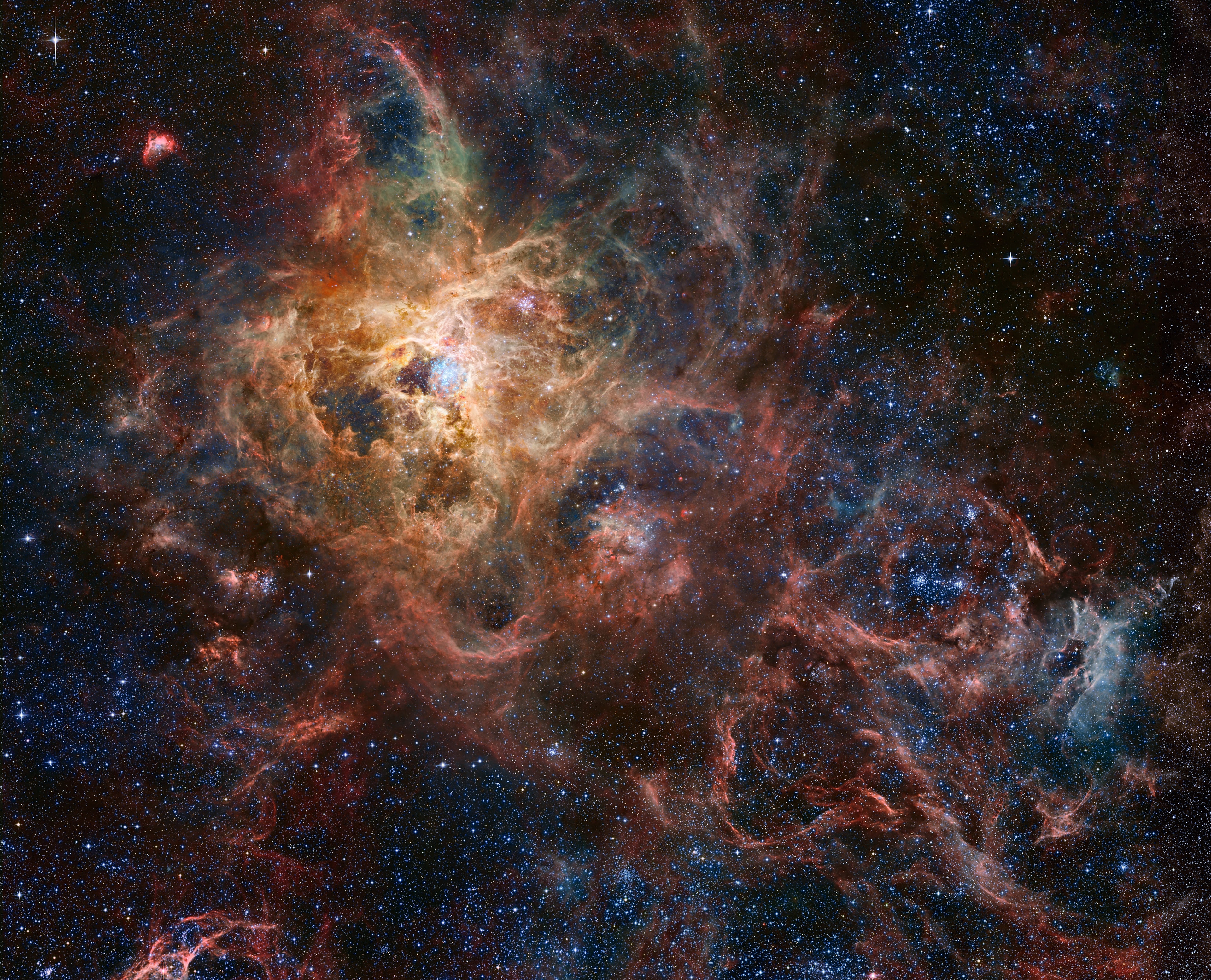 The Tarantula Nebula, also known as 30 Doradus, is more than a thousand light-years in diameter, a giant star forming region within nearby satellite galaxy the Large Magellanic Cloud. About 180 thousand light-years away, it's the largest, most violent star forming region known in the whole Local Group of galaxies. The cosmic arachnid sprawls across this magnificent view, an assembly of image data from large space- and ground-based telescopes. Within the Tarantula (NGC 2070), intense radiation, stellar winds, and supernova shocks from the central young cluster of massive stars cataloged as R136 energize the nebular glow and shape the spidery filaments. Around the Tarantula are other star forming regions with young star clusters, filaments, and blown-out bubble-shaped clouds. In fact, the frame includes the site of the closest supernova in modern times, SN 1987A, at lower right. The rich field of view spans about 2 degrees or 4 full moons in the southern constellation Dorado. But were the Tarantula Nebula closer, say 1,500 light-years distant like the Milky Way's own star forming Orion Nebula, it would take up half the sky.