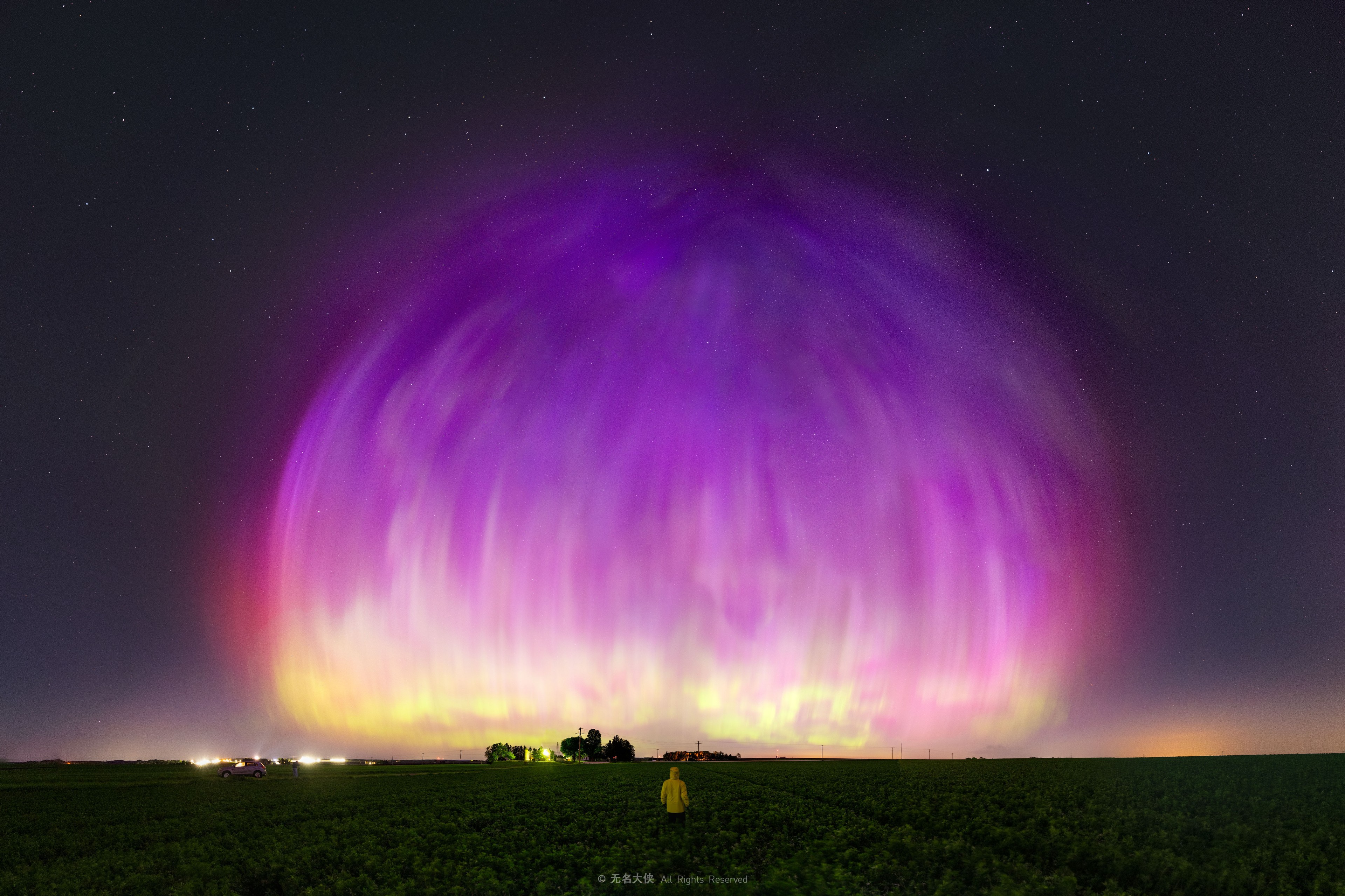 It seemed like night, but part of the sky glowed purple.  It was the now famous night of May 10, 2024, when people over much of the world reported beautiful aurora-filled skies. The featured image was captured this night during early morning hours from Arlington, Wisconsin, USA. The panorama is a composite of several 6-second exposures covering two thirds of the visible sky, with north in the center, and processed to heighten the colors and remove electrical wires. The photographer (in the foreground) reported that the aurora appeared to flow from a point overhead but illuminated the sky only toward the north. The aurora's energetic particles originated from CMEs ejected from our Sun over sunspot AR 3664 a few days before. This large active region rotated to the far side of the Sun last week, but may well survive to rotate back toward the Earth next week.