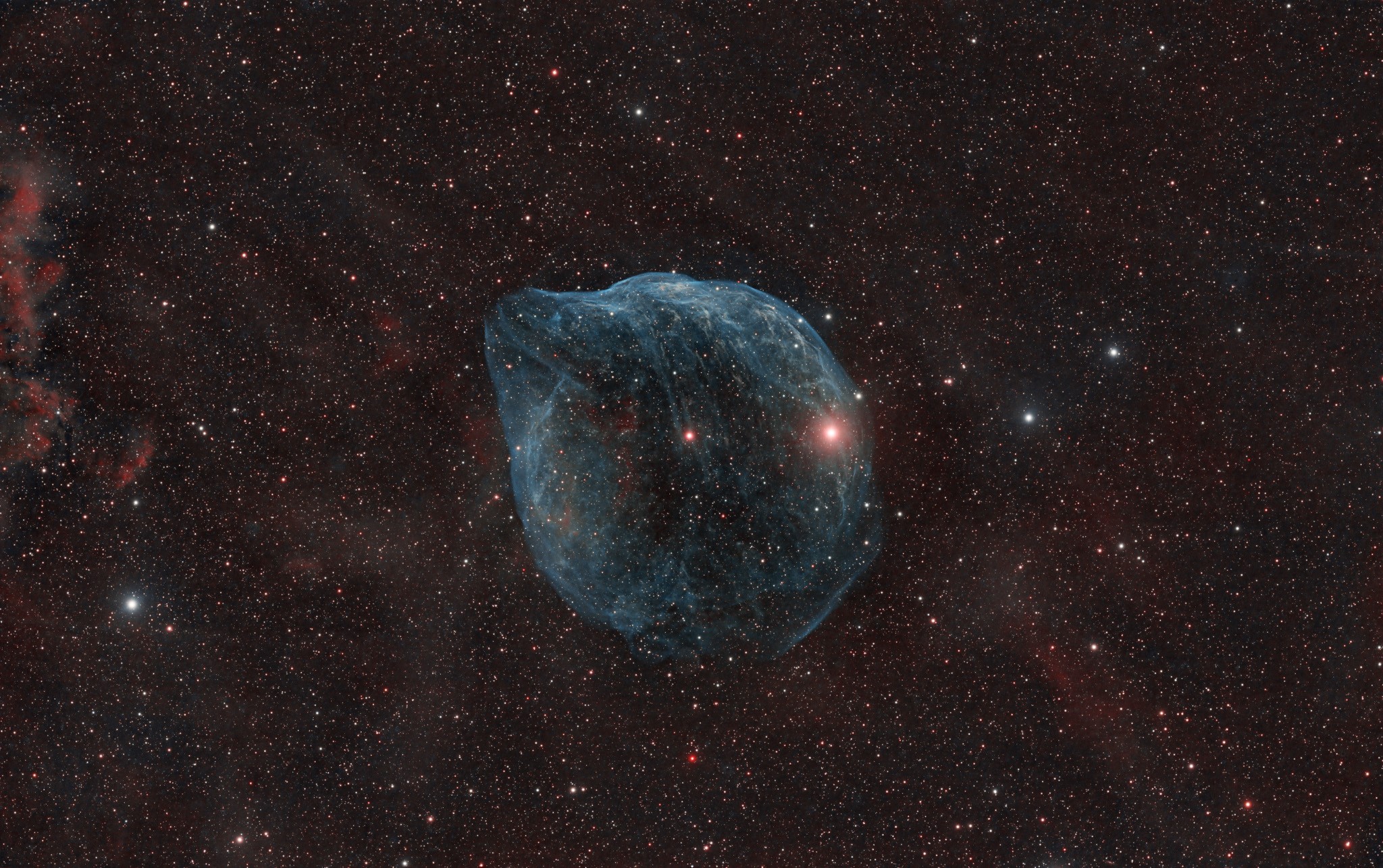 Blown by fast winds from a hot, massive star, this cosmic bubble is huge. Cataloged as Sharpless 2-308 it lies some 5,000 light-years away toward the well-trained constellation Canis Major and covers slightly more of the sky than a Full Moon. That corresponds to a diameter of 60 light-years at its estimated distance. The massive star that created the bubble, a Wolf-Rayet star, is the bright one near the center of the nebula. Wolf-Rayet stars have over 20 times the mass of the Sun and are thought to be in a brief, pre-supernova phase of massive star evolution. Fast winds from this Wolf-Rayet star create the bubble-shaped nebula as they sweep up slower moving material from an earlier phase of evolution. The windblown nebula has an age of about 70,000 years. Relatively faint emission captured by narrowband filters in the deep image is dominated by the glow of ionized oxygen atoms mapped to a blue hue. Presenting a mostly harmless outline, SH2-308 is also known as The Dolphin-head Nebula.