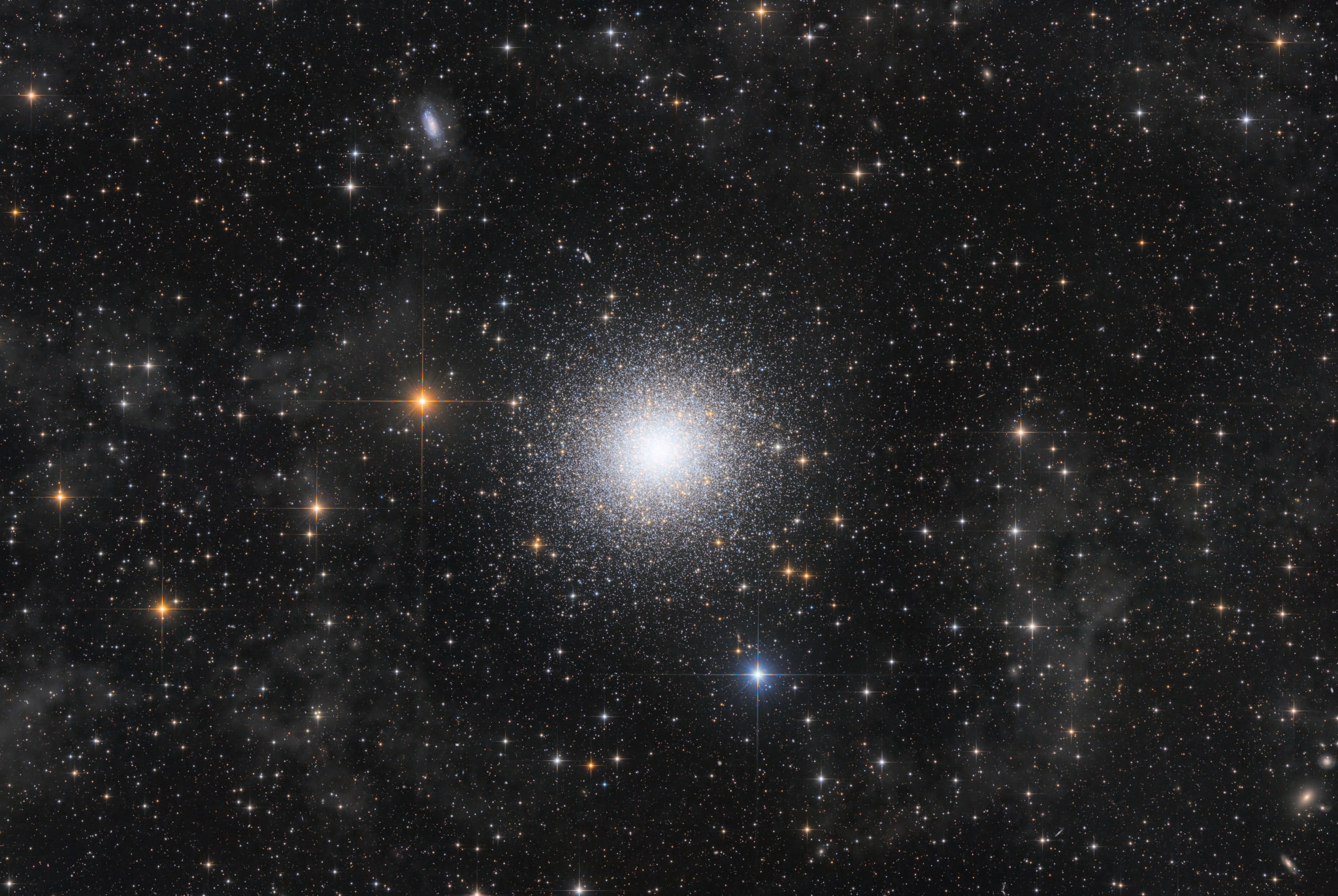 In 1716, English astronomer Edmond Halley noted, "This is but a little Patch, but it shows itself to the naked Eye, when the Sky is serene and the Moon absent." Of course, M13 is now less modestly recognized as the Great Globular Cluster in Hercules, one of the brightest globular star clusters in the northern sky. Sharp telescopic views like this one reveal the spectacular cluster's hundreds of thousands of stars. At a distance of 25,000 light-years, the cluster stars crowd into a region 150 light-years in diameter. Approaching the cluster core, upwards of 100 stars could be contained in a cube just 3 light-years on a side. For comparison, the closest star to the Sun is over 4 light-years away. The deep, wide-field image also reveals distant background galaxies including NGC 6207 at the upper left, and faint, foreground Milky Way dust clouds known to some as integrated flux nebulae.