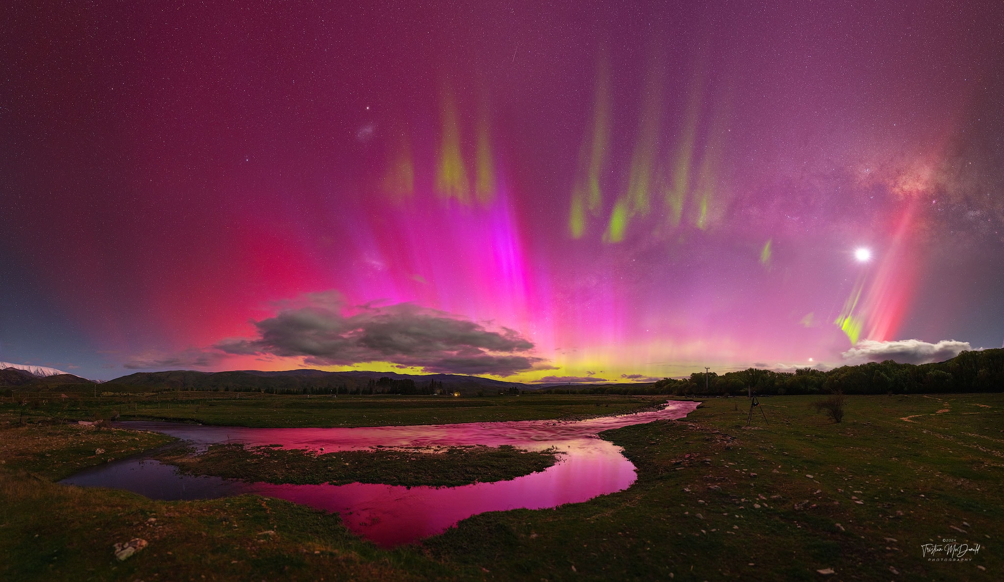 Sometimes the night sky is full of surprises. Take the sky over Lindis Pass, South Island, New Zealand one-night last week.  Instead of a typically calm night sky filled with constant stars, a busy and dynamic night sky appeared. Suddenly visible were pervasive red aurora, green picket-fence aurora, a red SAR arc, a STEVE, a meteor, and the Moon. These outshone the center of our Milky Way Galaxy and both of its two satellite galaxies: the LMC and SMC. All of these were captured together on 28 exposures in five minutes, from which this panorama was composed.  Auroras lit up many skies last week, as a Coronal Mass Ejection from the Sun unleashed a burst of particles toward our Earth that created colorful skies over latitudes usually too far from the Earth's poles to see them.  More generally, night skies this month have other surprises, showing not only auroras -- but comets.   Jigsaw Challenge: Astronomy Puzzle of the Day